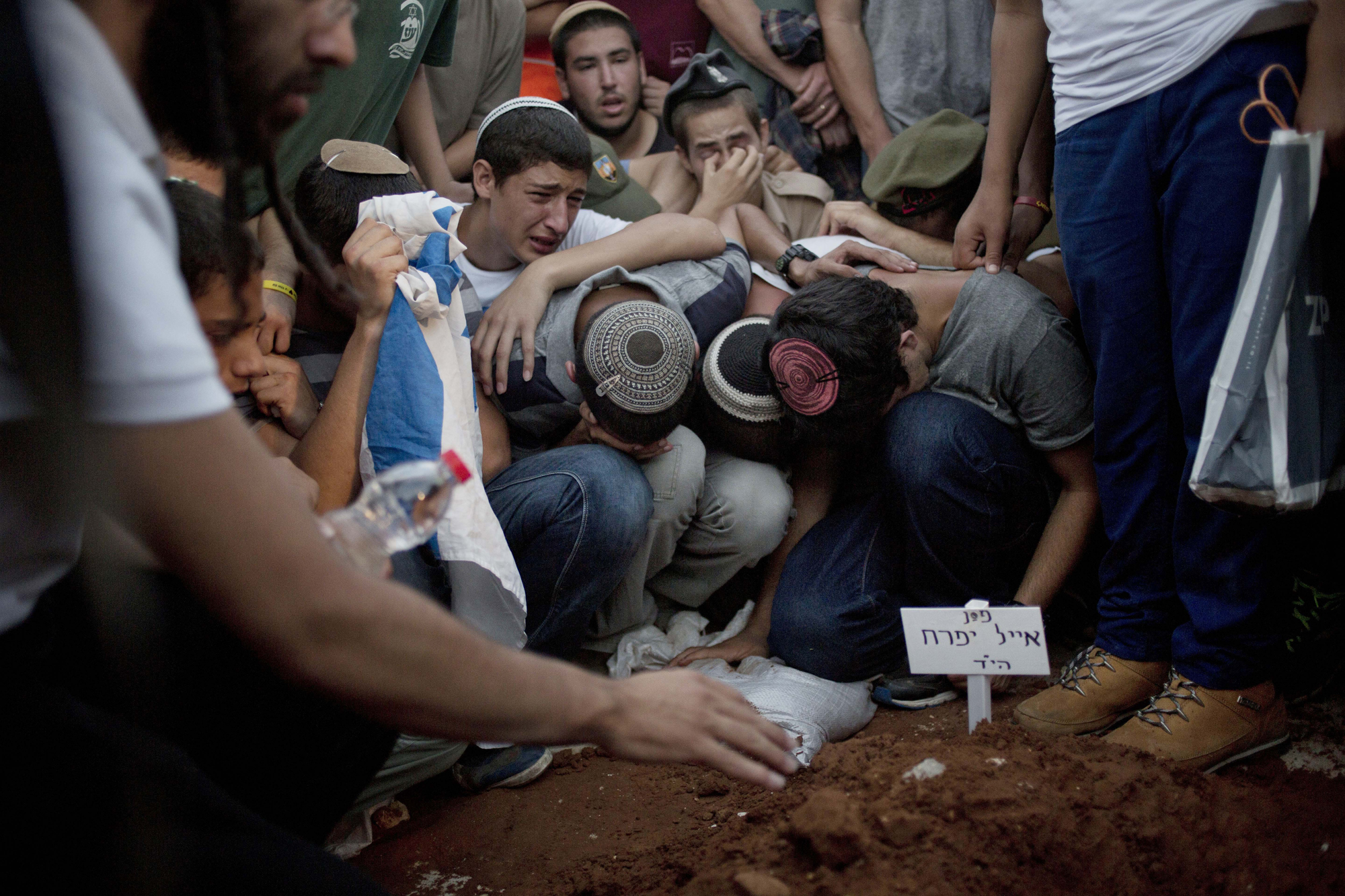 Family and friends of Eyal Yifrah, Gilad Shaar, and Naftali Fraenkel , three Israeli teenagers who were abducted over two weeks ago mourn over the grave of  Eyal Yifrah during their funeral in Modi'in, Israel, July 1.