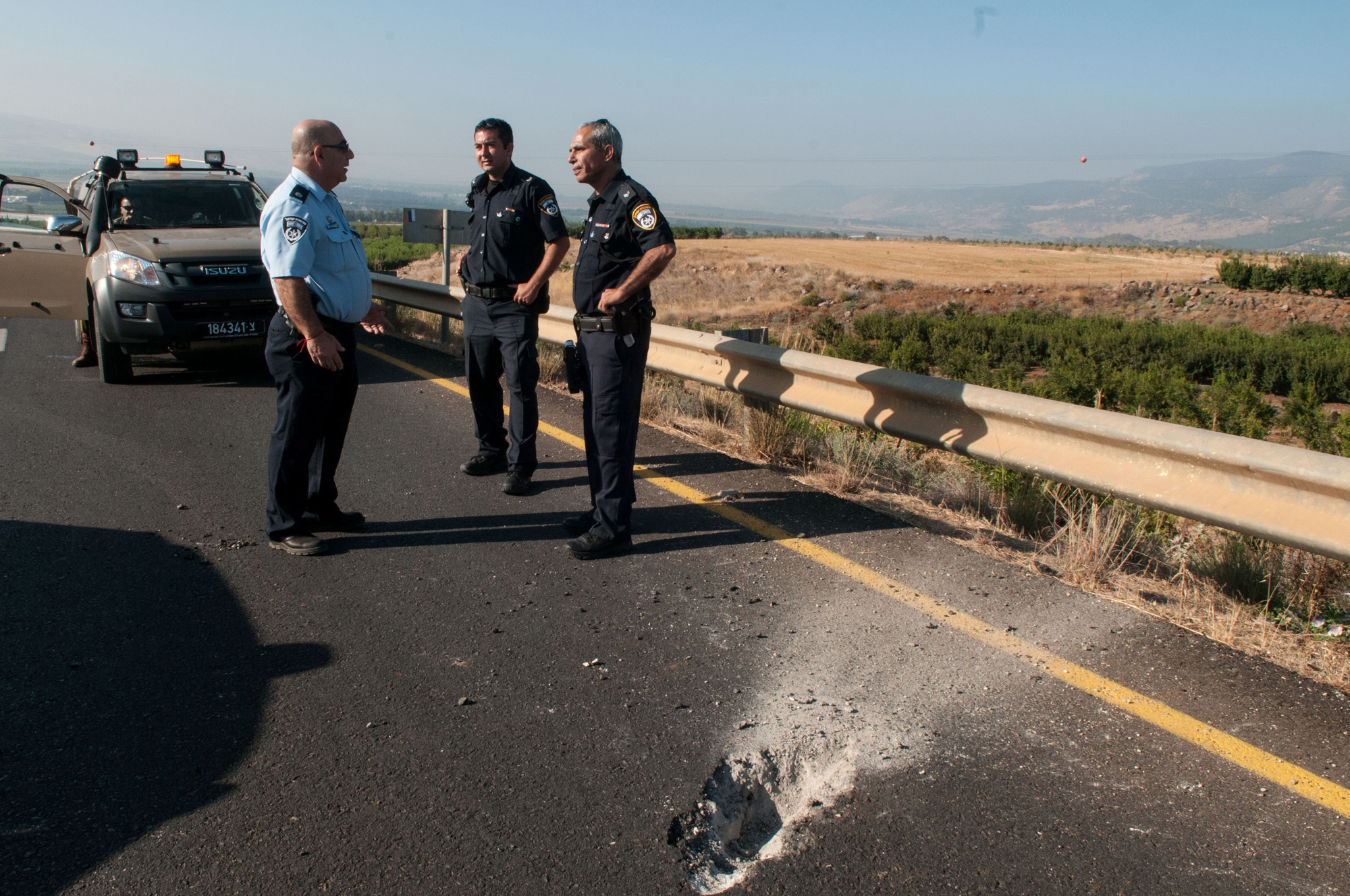 Israeli security forces stand next to damage caused by Katyusha style rocket fired from Lebanon near the border between northern Israel and Lebanon, on July 11, 2014.