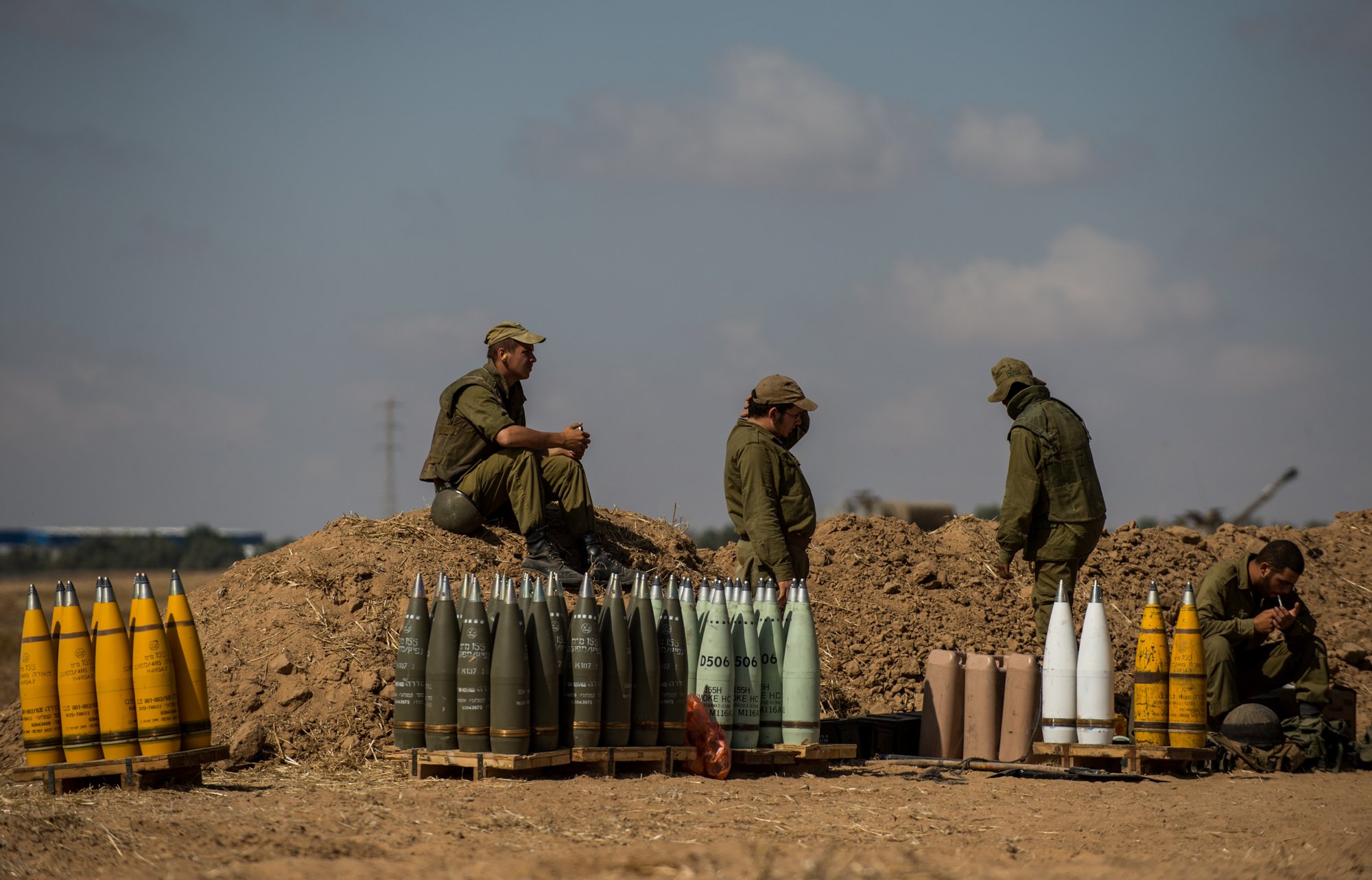 Israeli soldiers rest beside shells for a 155mm M109 Dores self-propelled howitzer at a position in Southern Israel near the border with Gaza, on the seventh day of Operation Protective Edge, on July 14, 2014. (Li Rui—Xinhua/Sipa)
