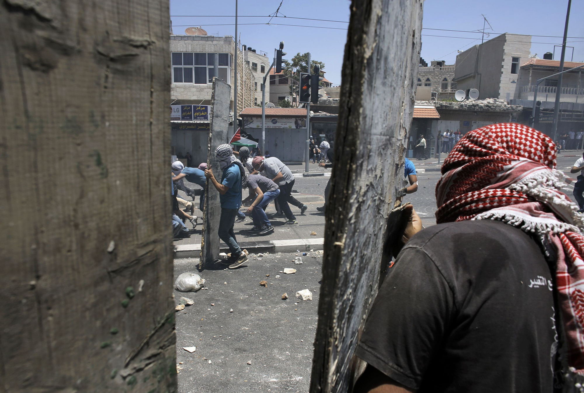 Palestinian stone-throwers take cover during clashes with Israeli police in Shuafat, an Arab suburb of Jerusalem, July 2.