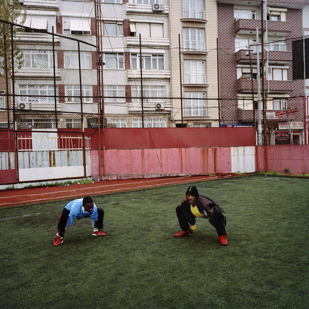 Sodiq and Adegeye, two Nigerian footballers living in Istanbul, stretch during an early evening practice on the rundown Feriköy pitch in April 2011 in the Kurtulus neighborhood of Istanbul, Turkey.