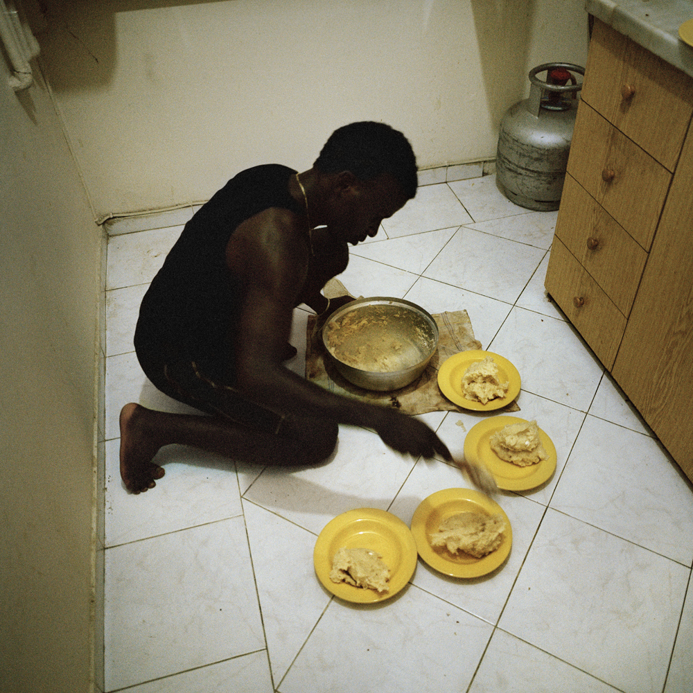 Akeem, A Nigerian footballer, prepares Banku; a Ghanian staple dish that's traditionally served with stew, on the floor of the apartment that he shares with seven other Nigerians inside the three room apartment located in the basement of a building in March 2013 in the Sisli neighborhood of Istanbul, Turkey.