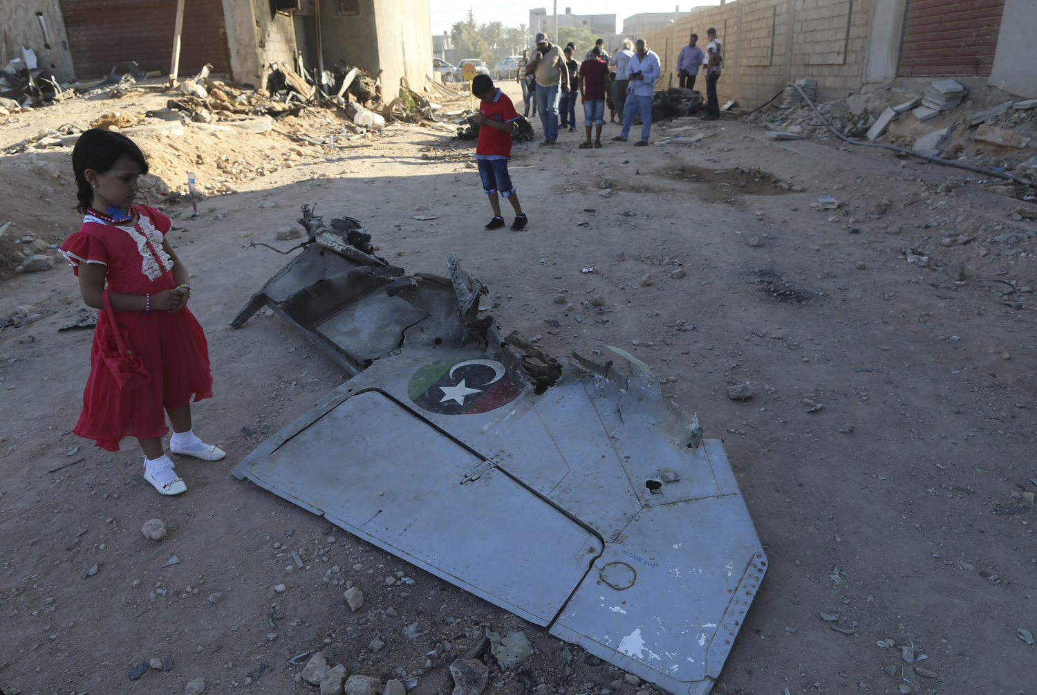 A girl stands next to the wreckage of a government MiG warplane which crashed during Tuesday's fighting, in Benghazi