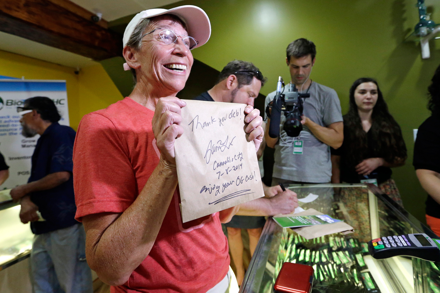 In this July 8, 2014, file photo, Deb Greene, 65, Cannabis City's first customer, displays her purchase of legal recreational marijuana at the store in Seattle. (Elaine Thompson – AP)