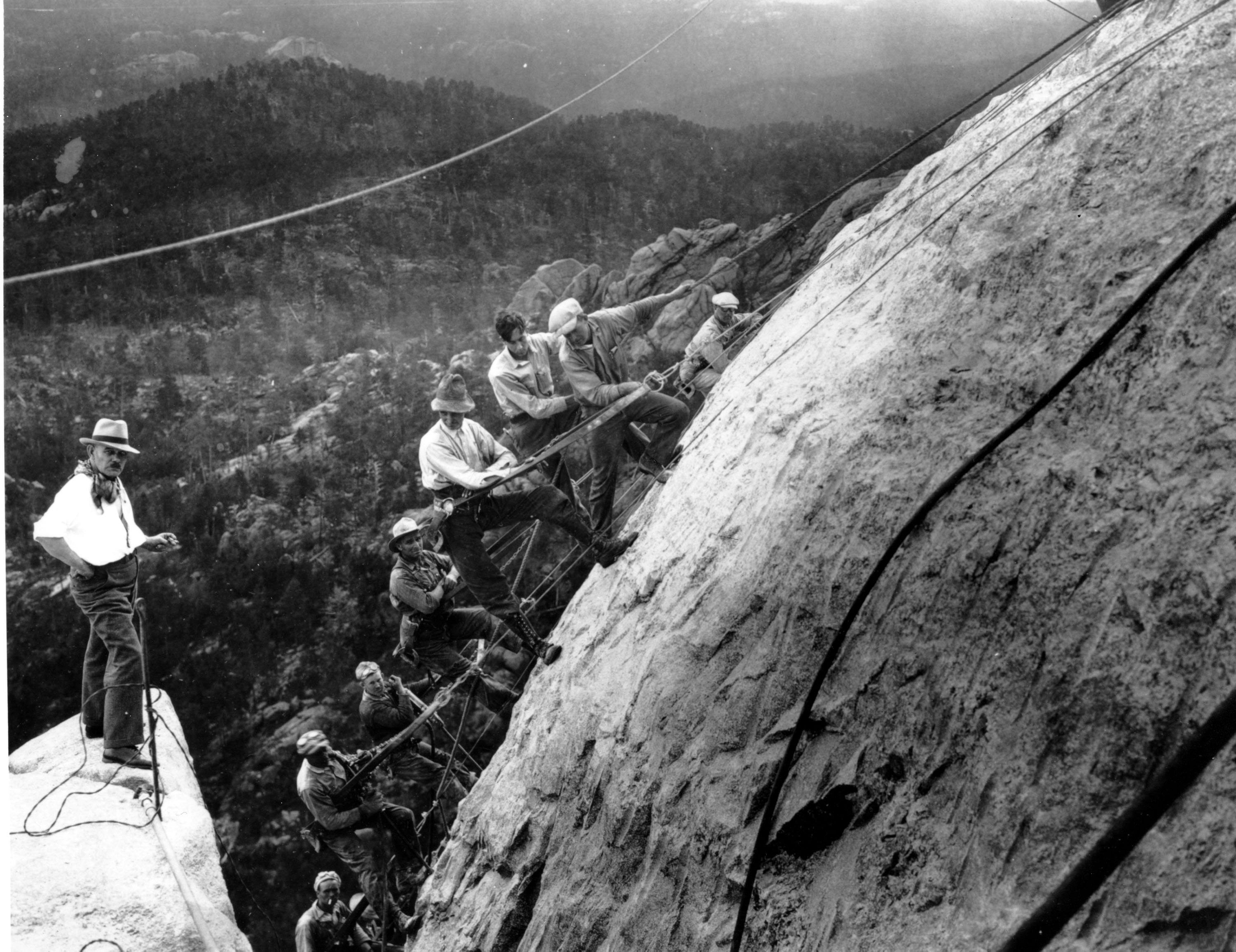Drillers, suspended in slins fastened with cables to the winches at the top of the mountain, work on the George Washington head of the Mount Rushmore Memorial in the Black Hills area of Keystone, S.D. on July, 22, 1929.