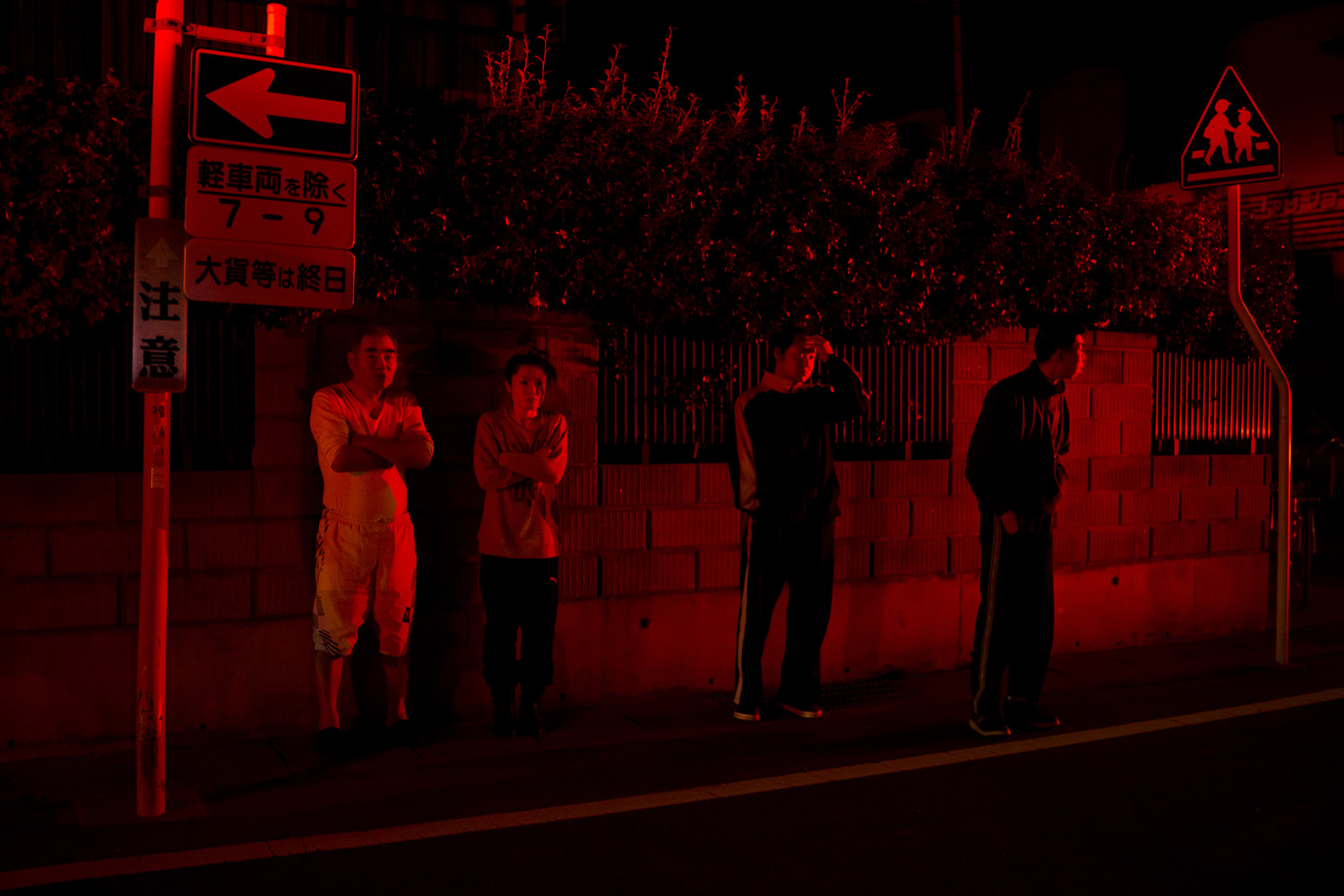 Japan, Fukushima City, 2014Residents stand on the street while rescue teams try and get into a one bedroom apartment after a part time decontamination worker locked himself into his apartment and committed suicide by breathing in burning charcoal on the 1st of April shortly after 9pm.