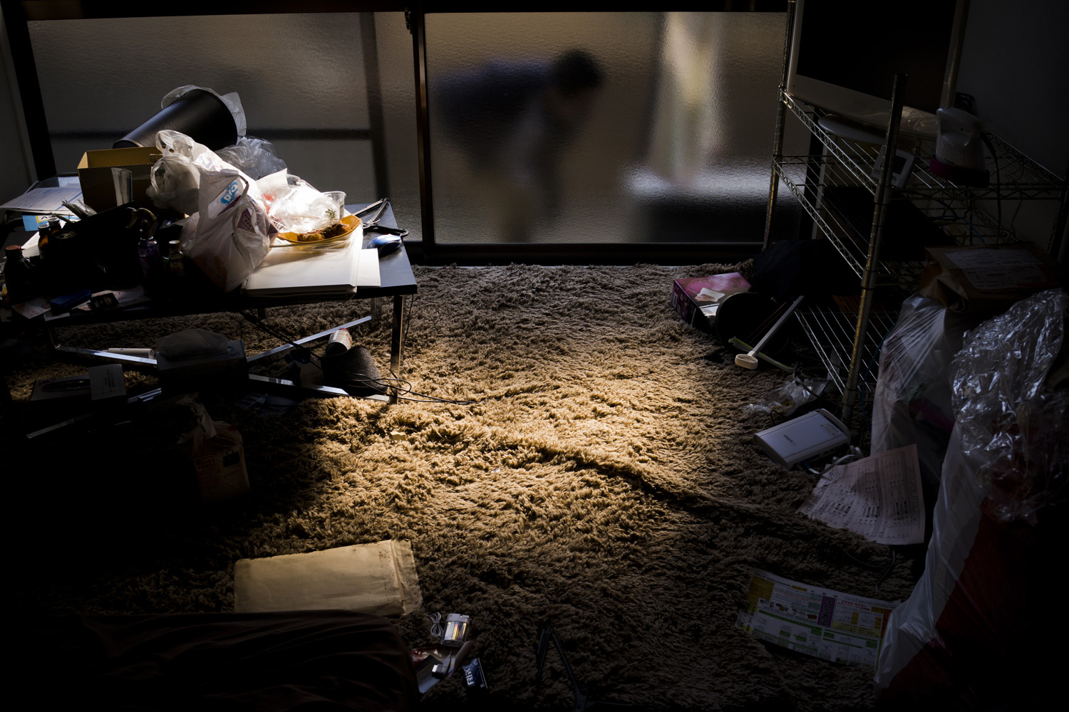 Japan, Fukushima City, 2014. The landlord checks the outside window of a one bedroom apartment rented to a decontamination worker who committed suicide by deliberately breathing in carbon monoxide the night before. Suicides in Fukushima have been on the rise since the Fukushima Daiichi Nuclear Power Station in 2011.