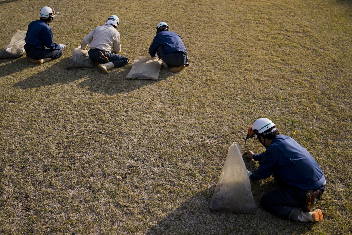 Japan, Ikata, 2014. Workers cut grass by hand at the Ikata Nuclear Power Station by Shikoku Electric Power Co., located on the southern coastline of Japan.