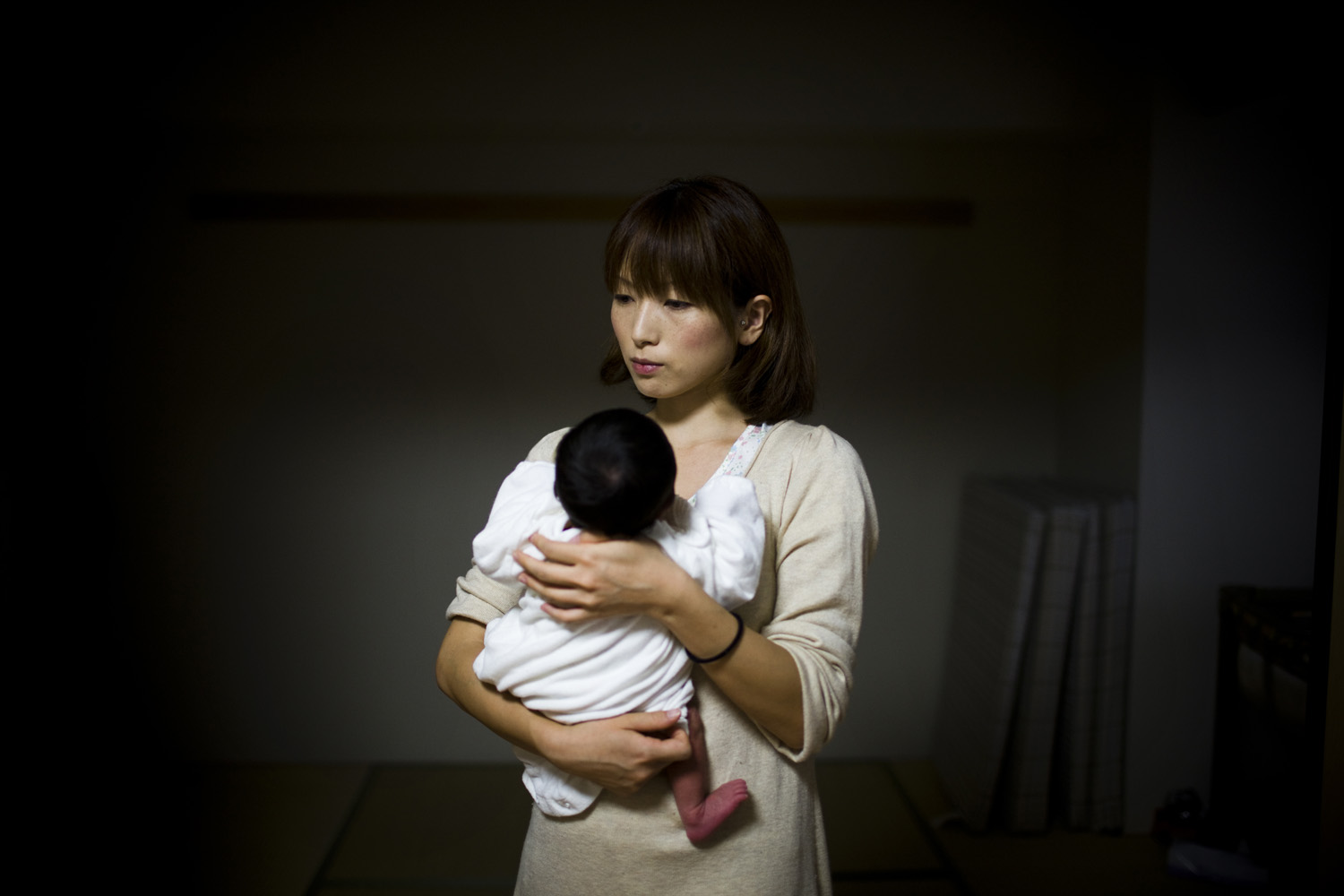 Japan, Tokyo, 2011. Sachiko Masuyama holds her newborn baby in her home in Shinonome, Tokyo. She relocated to Tokyo after evacuating her previous home near the damaged Fukushima Daiichi Nuclear Power Station. She discovered she was pregnant two days before the earthquake and tsunami hit the northeastern coast of Japan.