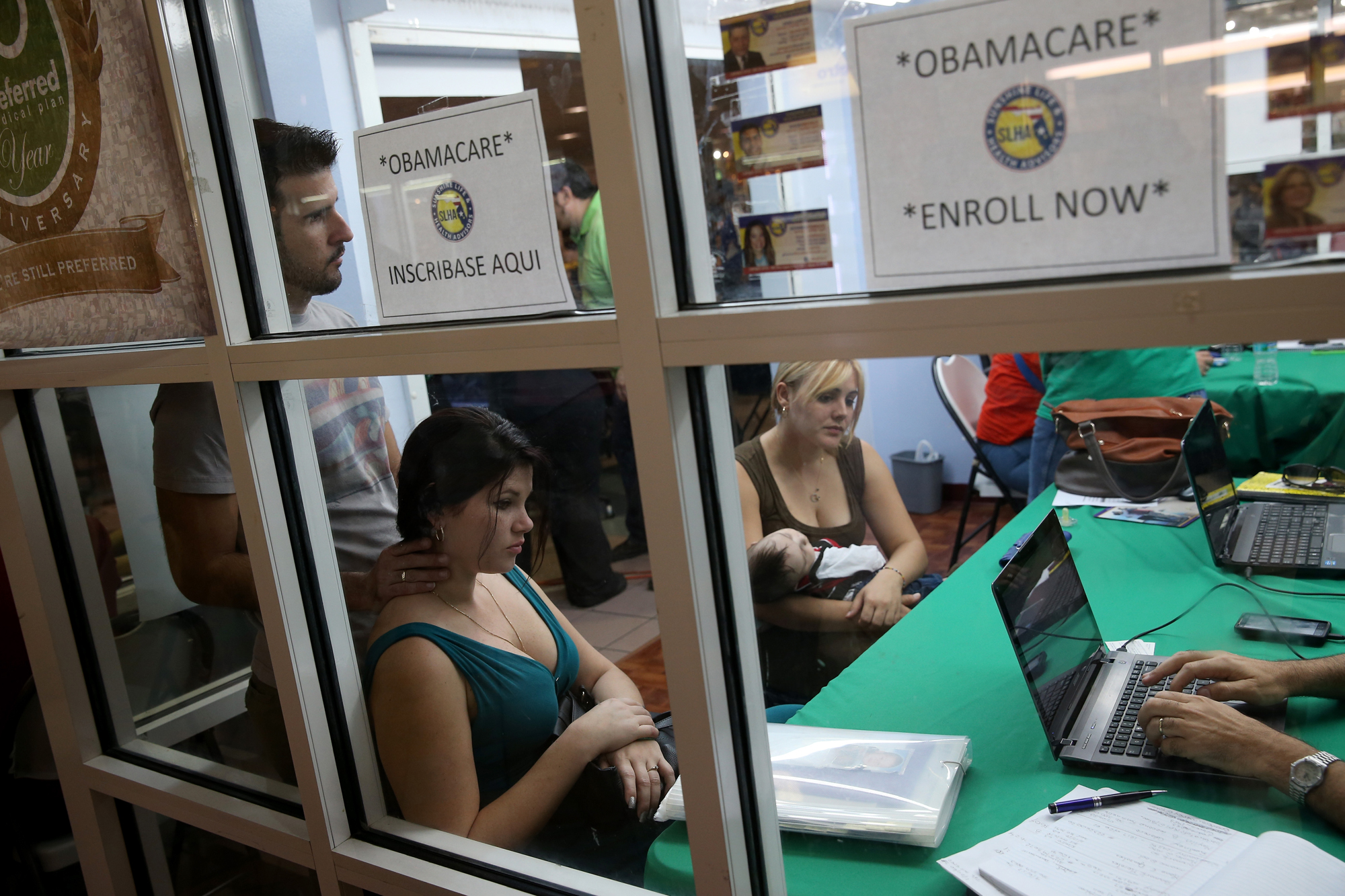 Ronnie Cabrera, Dailem Delombard and Maylin Lezcano holding Lucas Cabrera sit with an insurance agent from Sunshine Life and Health Advisors as they try to purchase health insurance under the Affordable Care Act at the kiosk setup at the Mall of Americas on January 15, 2014 in Miami.