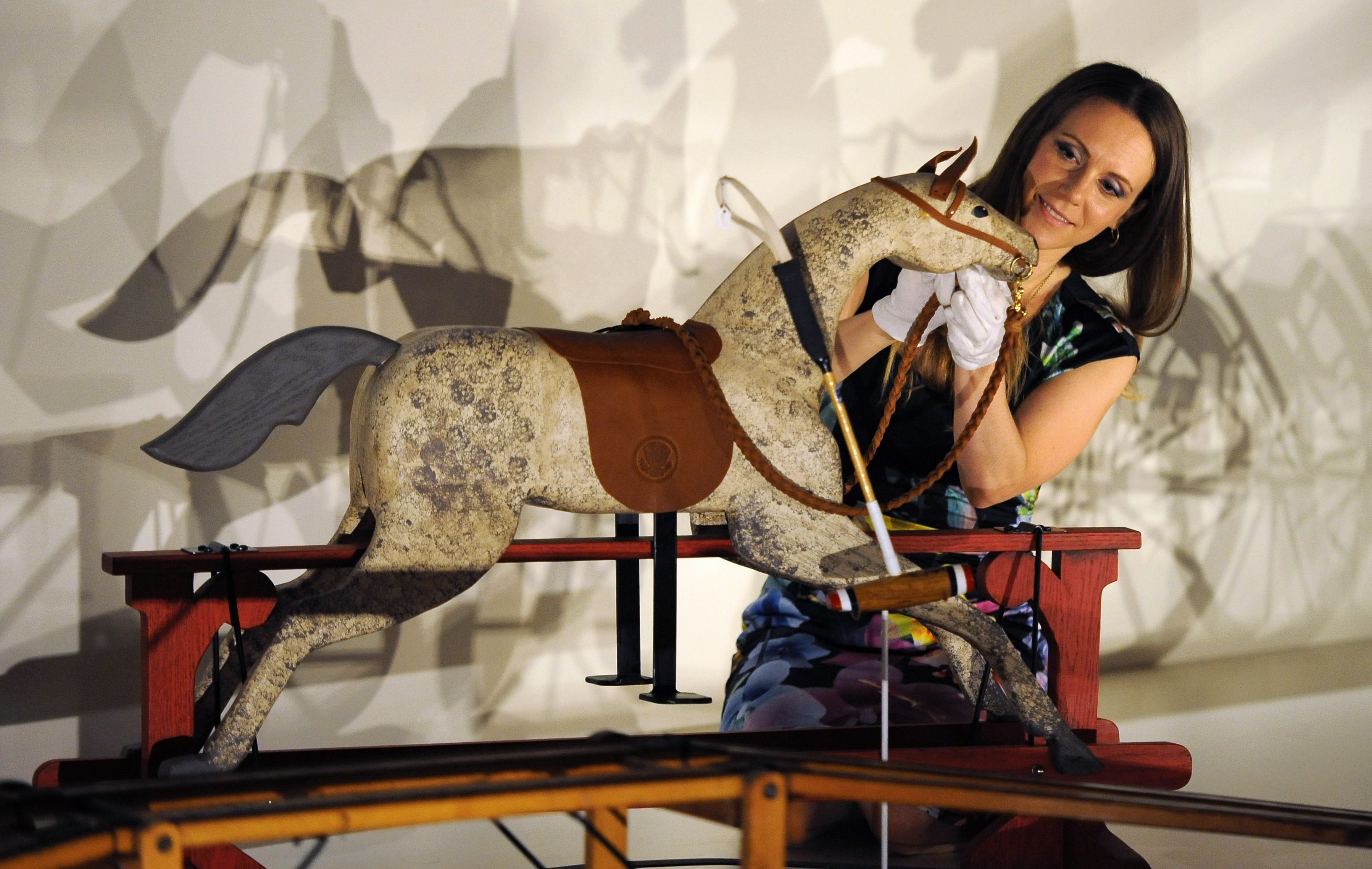 Curator Anna Reynolds adds the finishing touches to a rocking horse presented to Prince George of Cambridge by U..S President Barak Obama and his wife Michelle Obama at the 'Royal Childhood' exhibition at Buckingham Palace in London on July 24, 2014.