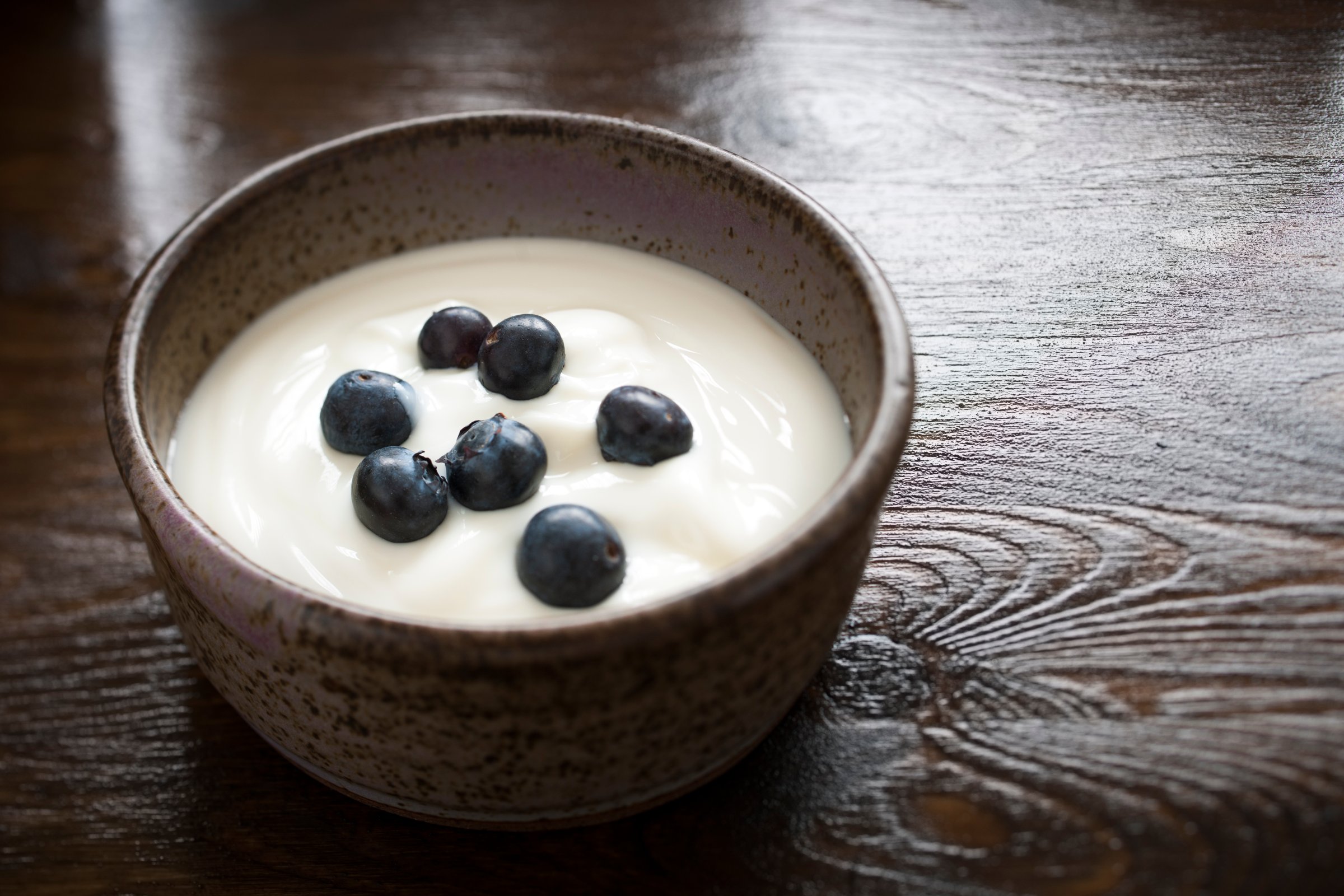 A rustic bowl of natural yogurt with blueberries