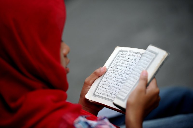 An Indonesian Muslim girl reads the Quran as she waits for the breaking of the fast during Ramadan on July 6, 2014 in Surabaya, Indonesia.