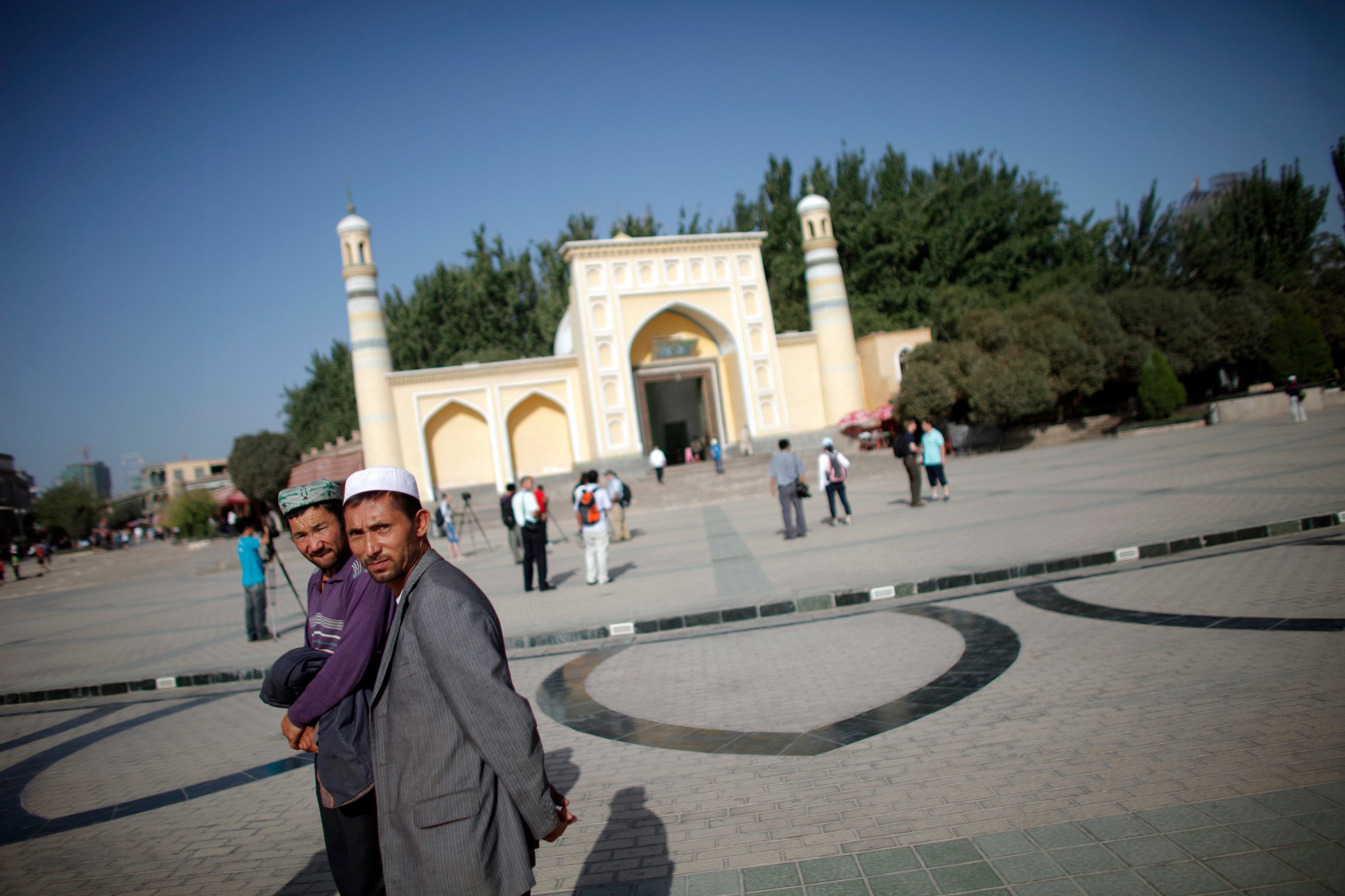 Ethnic Uighur men walk outside a mosque in Kashgar