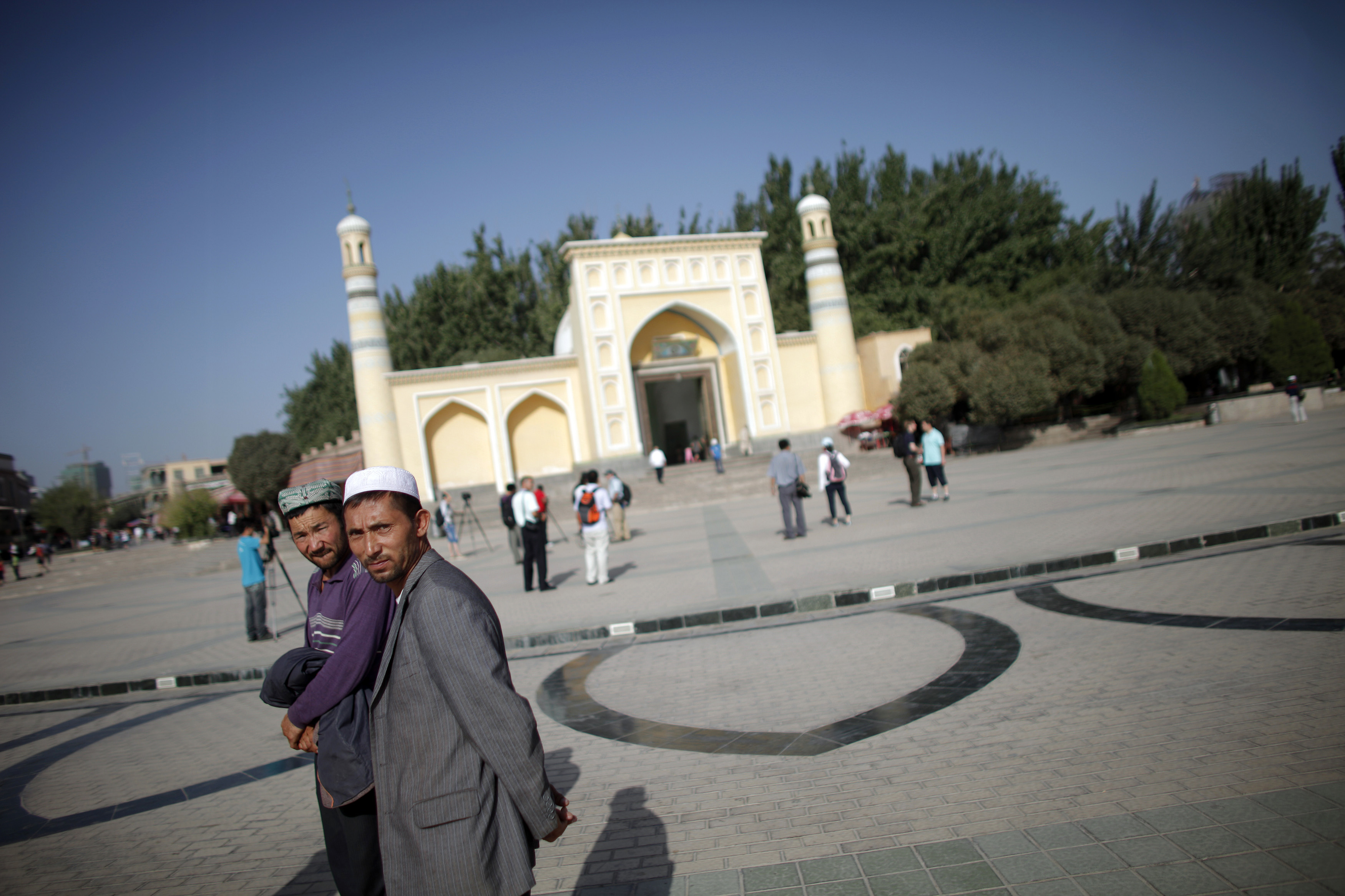 Ethnic Uighur men walk outside a mosque in Kashgar