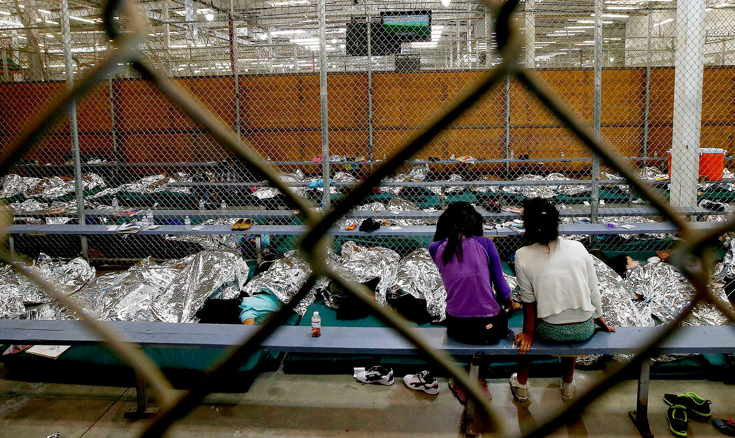 Two young girls watch a World Cup soccer match on a television from their holding area where hundreds of mostly Central American immigrant children are being processed and held at the U.S. Customs and Border Protection Nogales Placement Center in Nogales