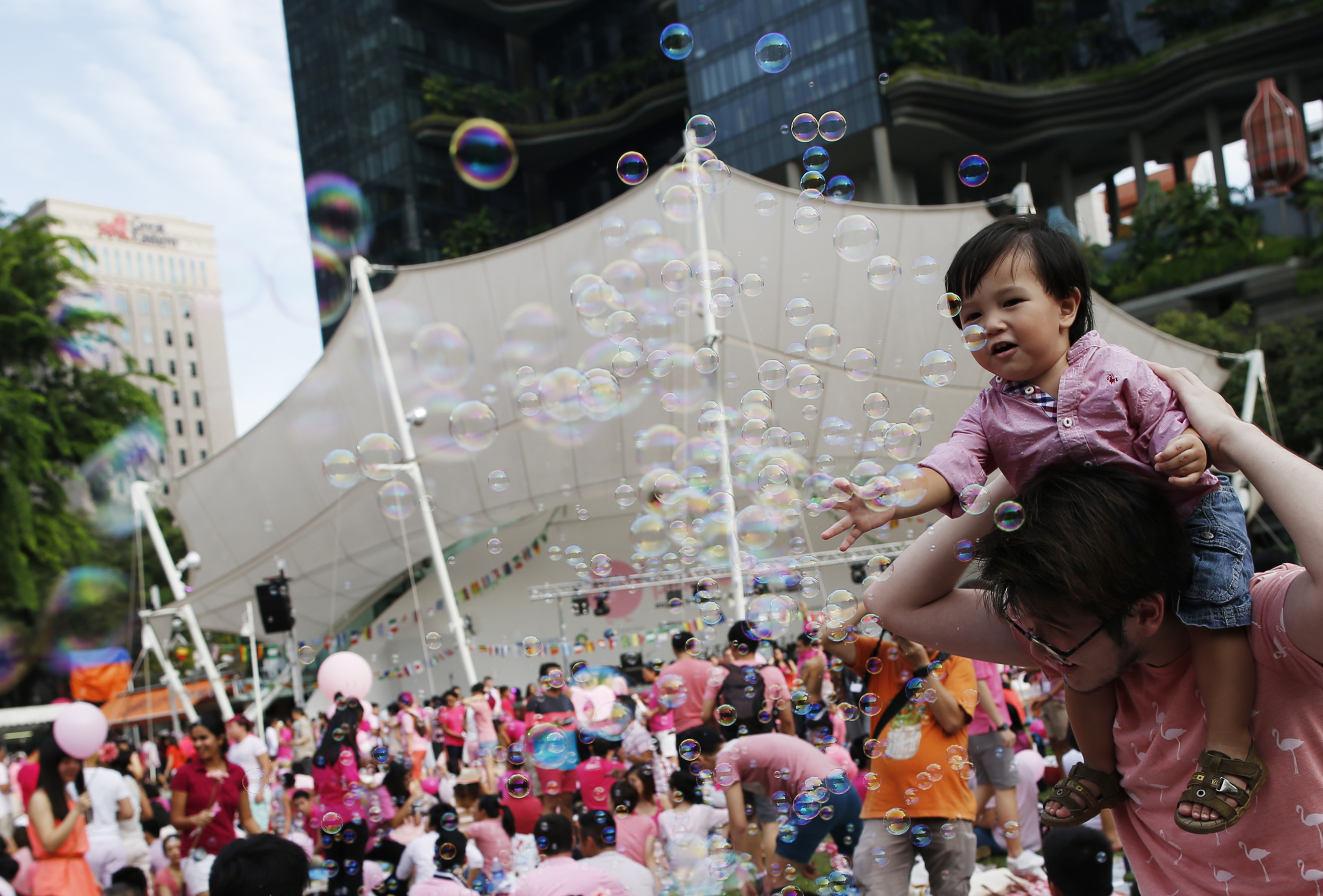 Toddler plays with bubbles as participants wait to take part in the forming of a giant pink dot at the Speakers' Corner in Hong Lim Park in Singapore