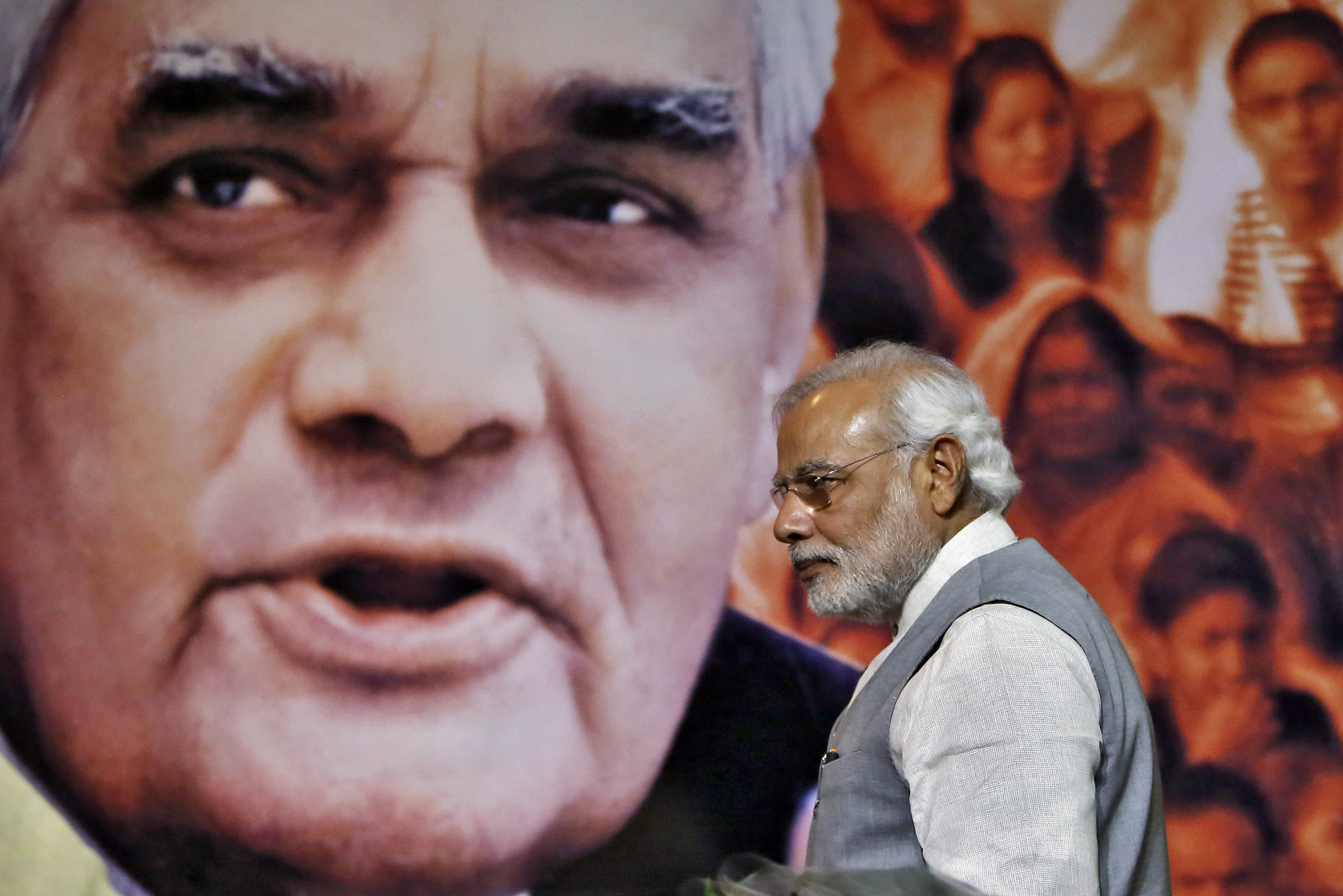 Indian Prime Minister Narendra Modi walks in front of a picture of former Indian Prime Minister Atal Bihari Vajpayee after a news conference in New Delhi on July 9, 2014. (Anindito Mukherjee—Reuters)