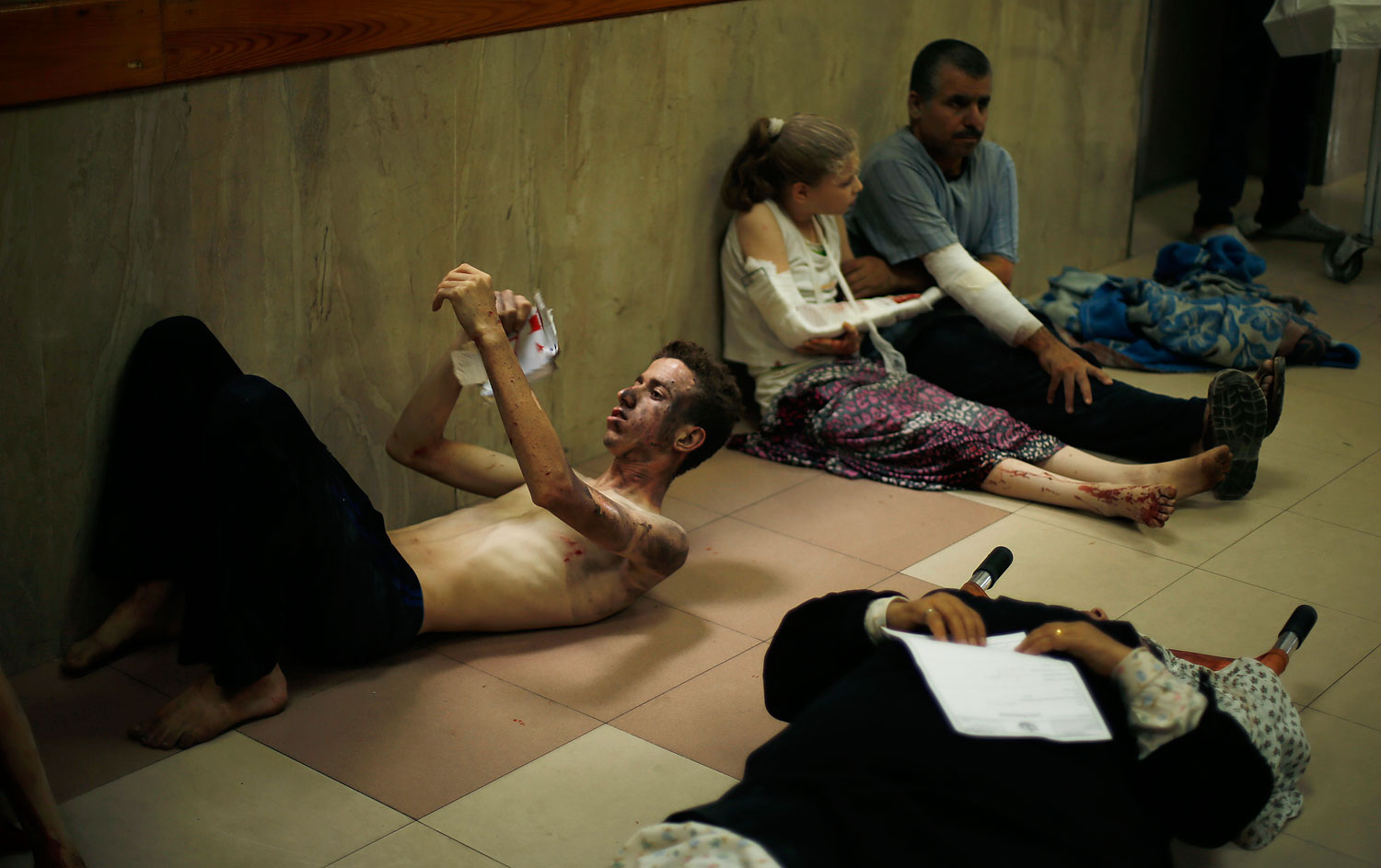 Palestinians, who medics said were wounded during heavy Israeli shelling, sit at a hospital in Gaza City July 20, 2014.