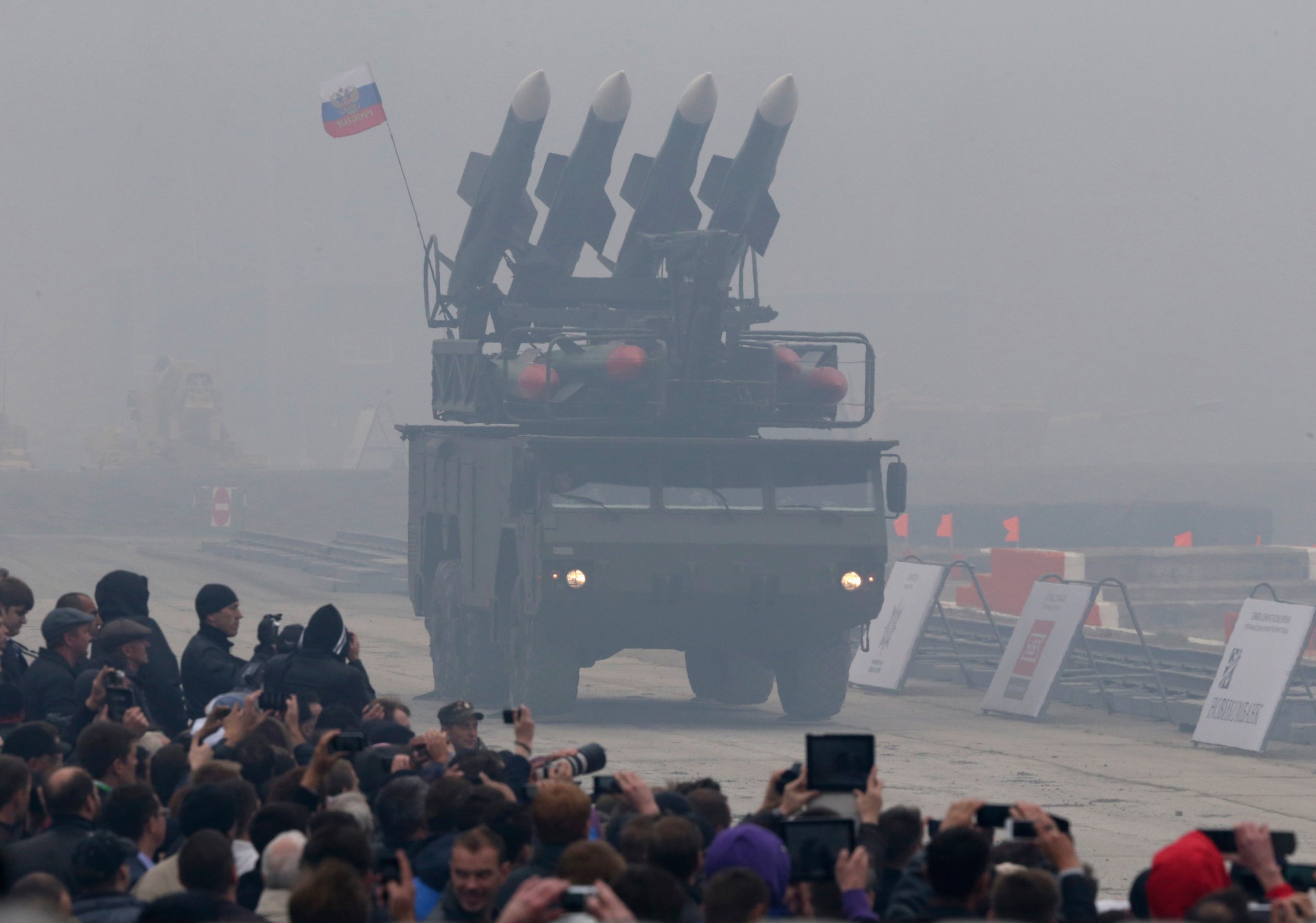 Spectators watch a Russian "Buk" missile system being driven during the "Russia Arms Expo 2013" 9th international exhibition of arms, military equipment and ammunition, in the Urals city of Nizhny Tagil