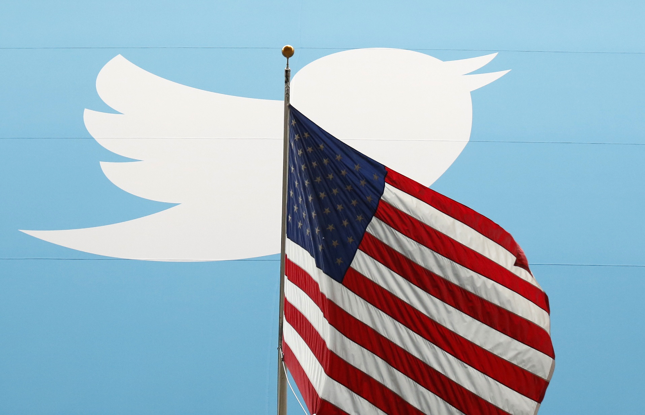 The Twitter Inc. logo is shown with the U.S. flag during the company's IPO on the floor of the New York Stock Exchange in New York