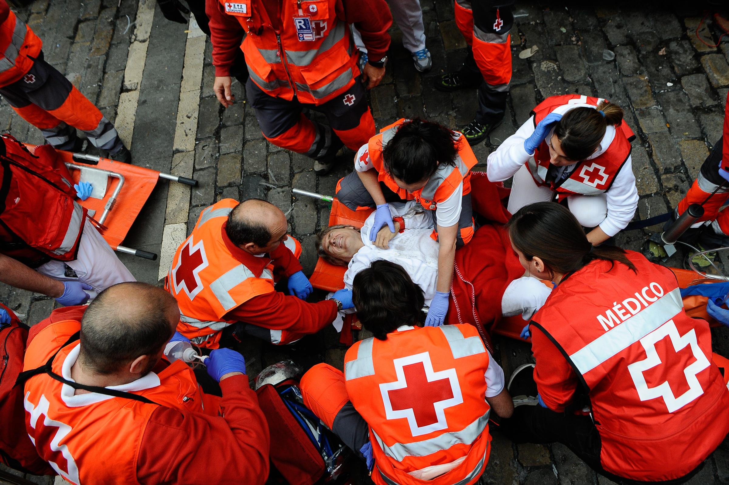 A wounded man is treated by Red Cross health services during the running of the bulls of the San Fermin festival on July 7, 2014 in Pamplona, Spain.
