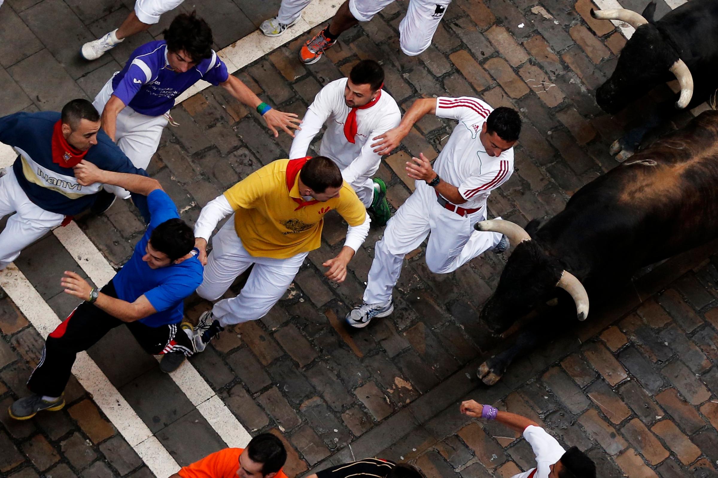 Revelers are chased by Dolores Aguirre's ranch fighting bulls during the running of the bulls of the San Fermin festival in Pamplona, Spain on July 8, 2014.