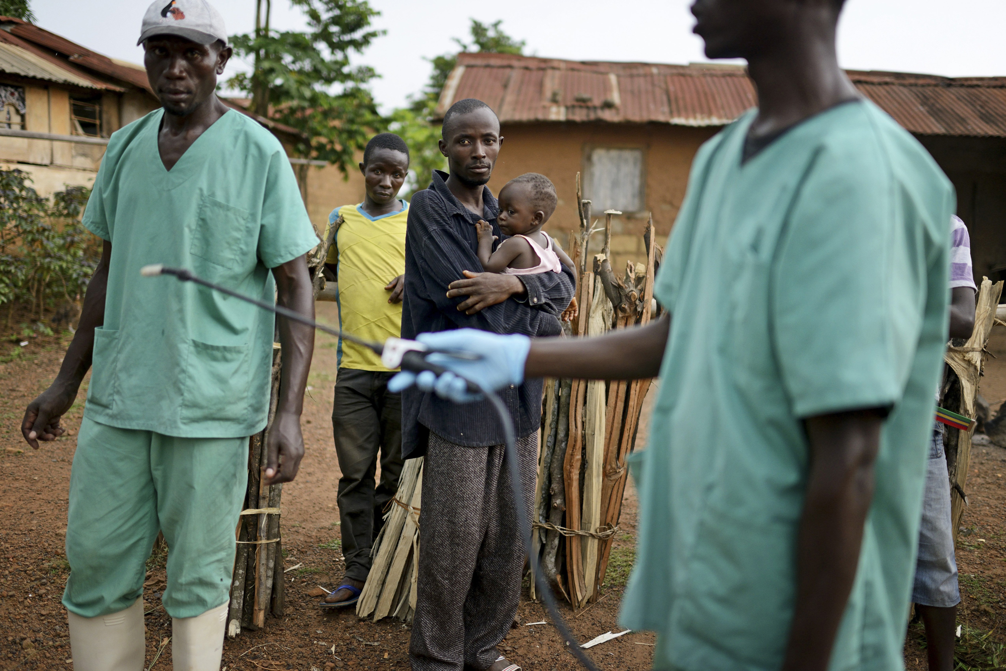Locals watch workers with Doctors Without Borders as they disinfect after leaving a private clinic, where they've been working to combat the spread of the Ebola virus, Teldou, Guinea, July 10, 2014.