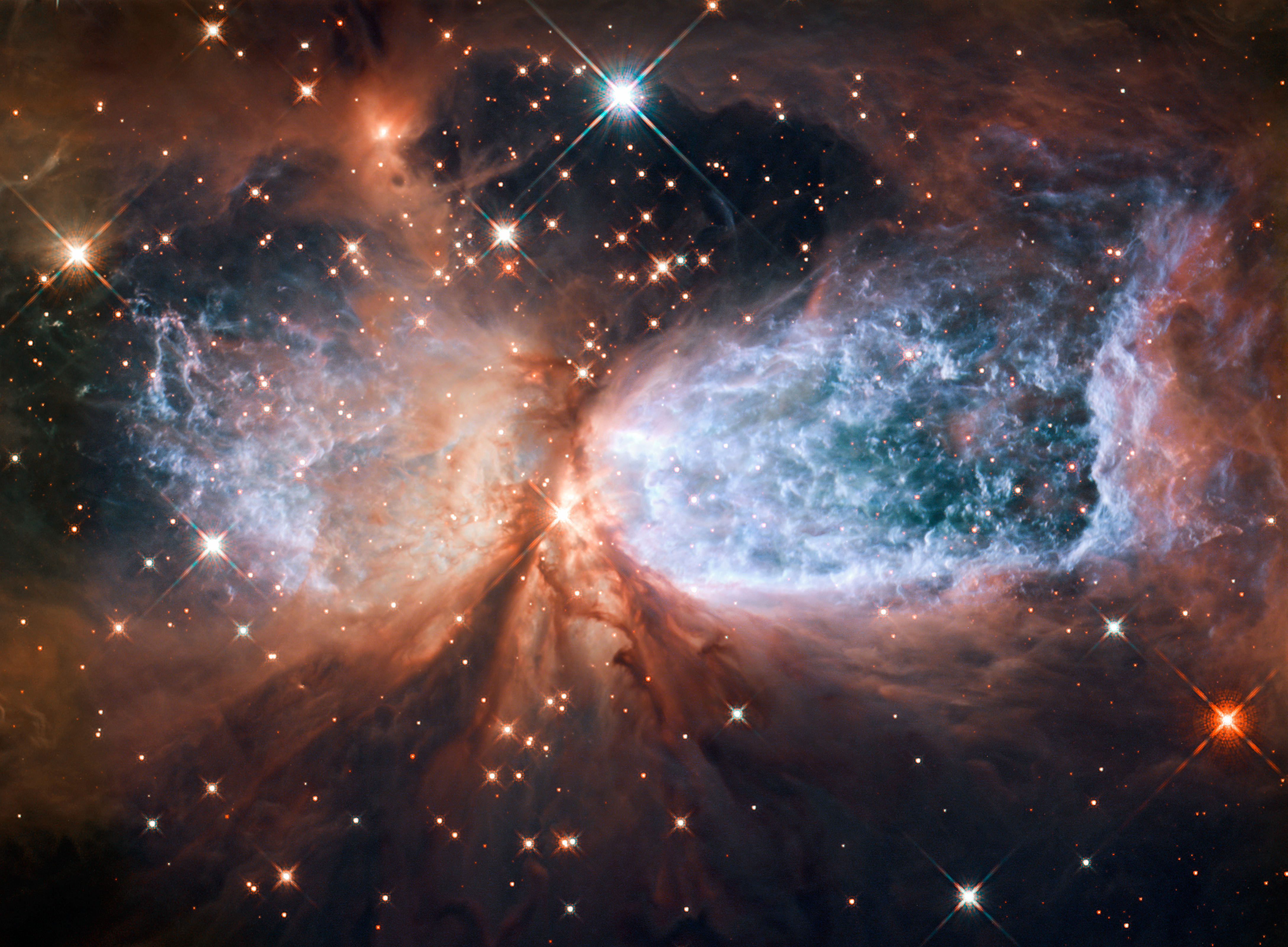 This is a compact star forming region in the constellation Cygnus. A newly-formed star called S106 IR is shrouded in dust at the centre of the image, and is responsible for the surrounding gas cloud’s hourglass-like shape and the turbulence visible within. Light from glowing hydrogen is coloured blue in this image.