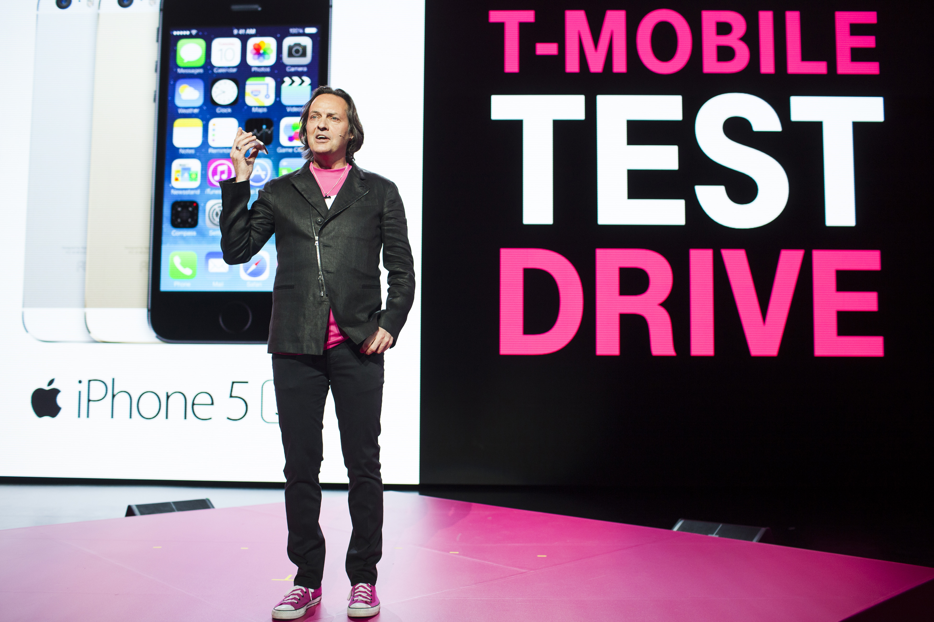 John Legere, chief executive officer of T-Mobile US Inc., holds an Apple Inc. iPhone as he speaks during an event in Seattle, Washington, U.S., on Wednesday, June 18, 2014. (Bloomberg/Getty Images)