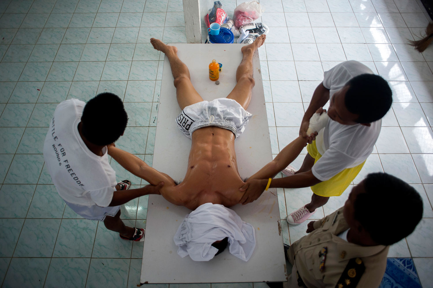 Assistants carry out a massage on an inmate before his fight as a prison officer stands by at Klong Pai prison on July 12, 2014 in Nakhon Ratchasima, Thailand.