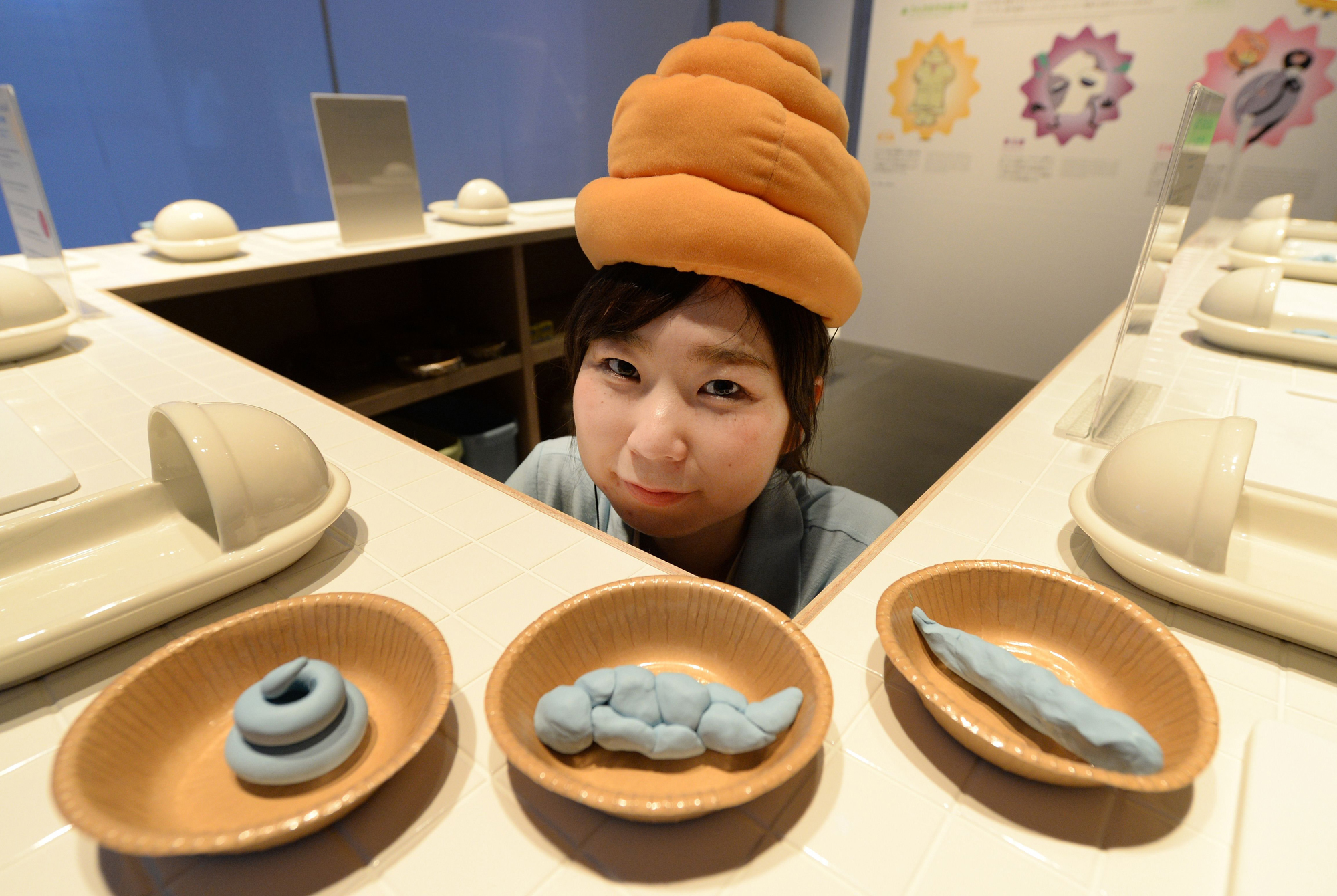 A staff member wearing a poo-shaped hat poses at a toilet exhibition at the National Museum of Emerging Science and Innovation in Tokyo on July 9, 2014.