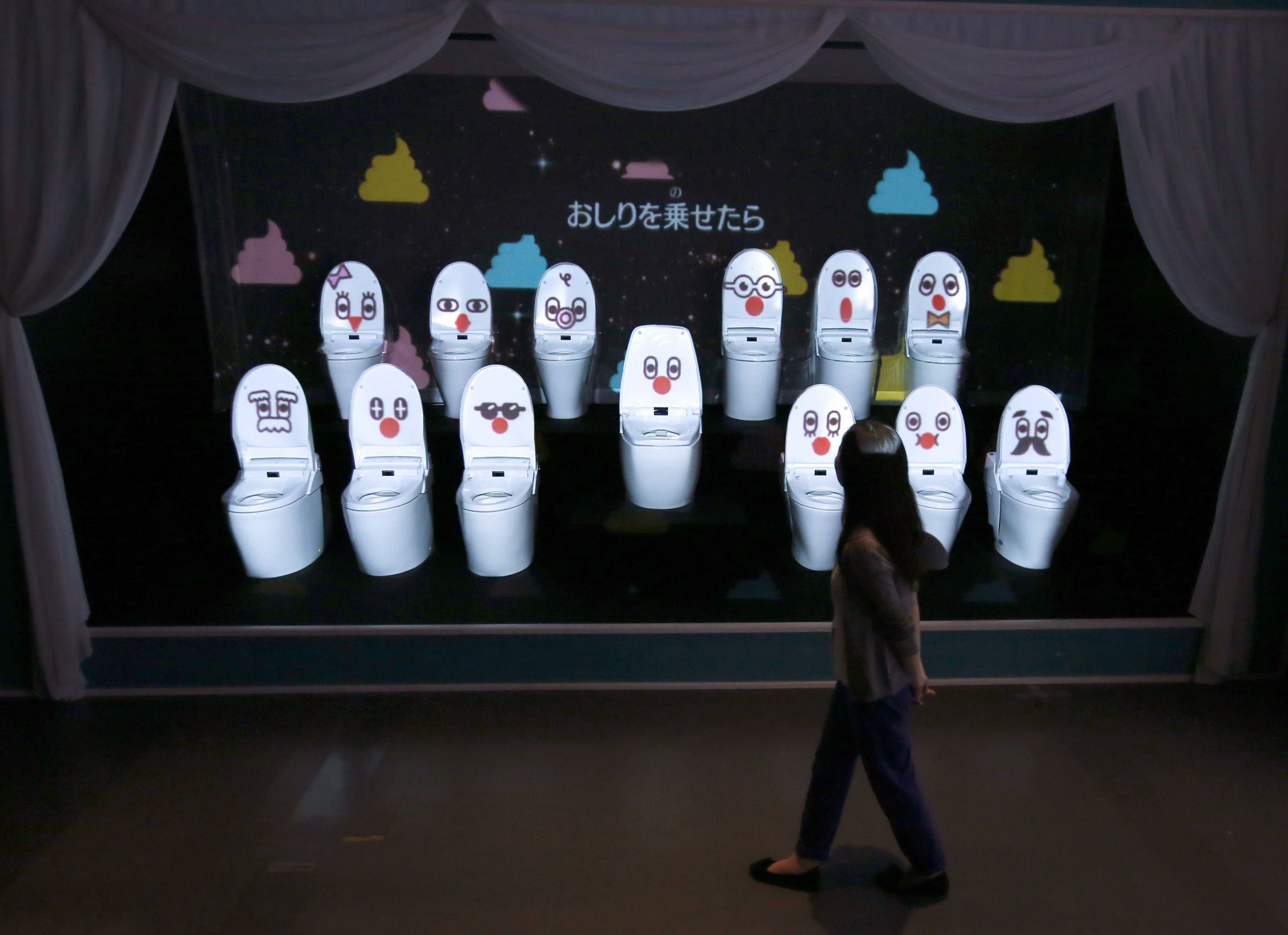A woman walks past a choir of toilets that sing to thank visitors for putting in the effort of trying to learn more about what is normally a taboo topic of sitting on them, at an exhibition titled "Toilet !? Human Waste and Earth's Future" at the Miraikan National Museum of Emerging Science and Innovation in Tokyo July 3, 2014.