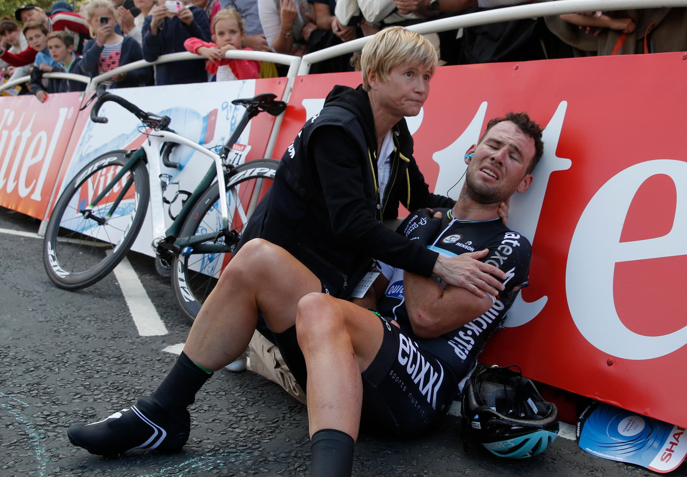 Omega Pharma-Quick Step team rider Mark Cavendish of Britain gets assistance after crashing during a mass sprint next to the finish line of the first 190.5 km stage of the Tour de France cycling race from Leeds to Harrogate on July 5, 2014.