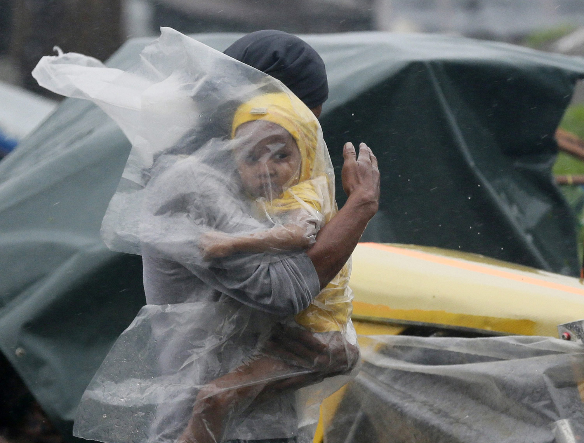 A Filipino father with his child covered under a plastic sheet flee the strong winds and rain brought by typhoon Rammasun in the Tondo slum area, in Manila, Philippines, July 16, 2014.