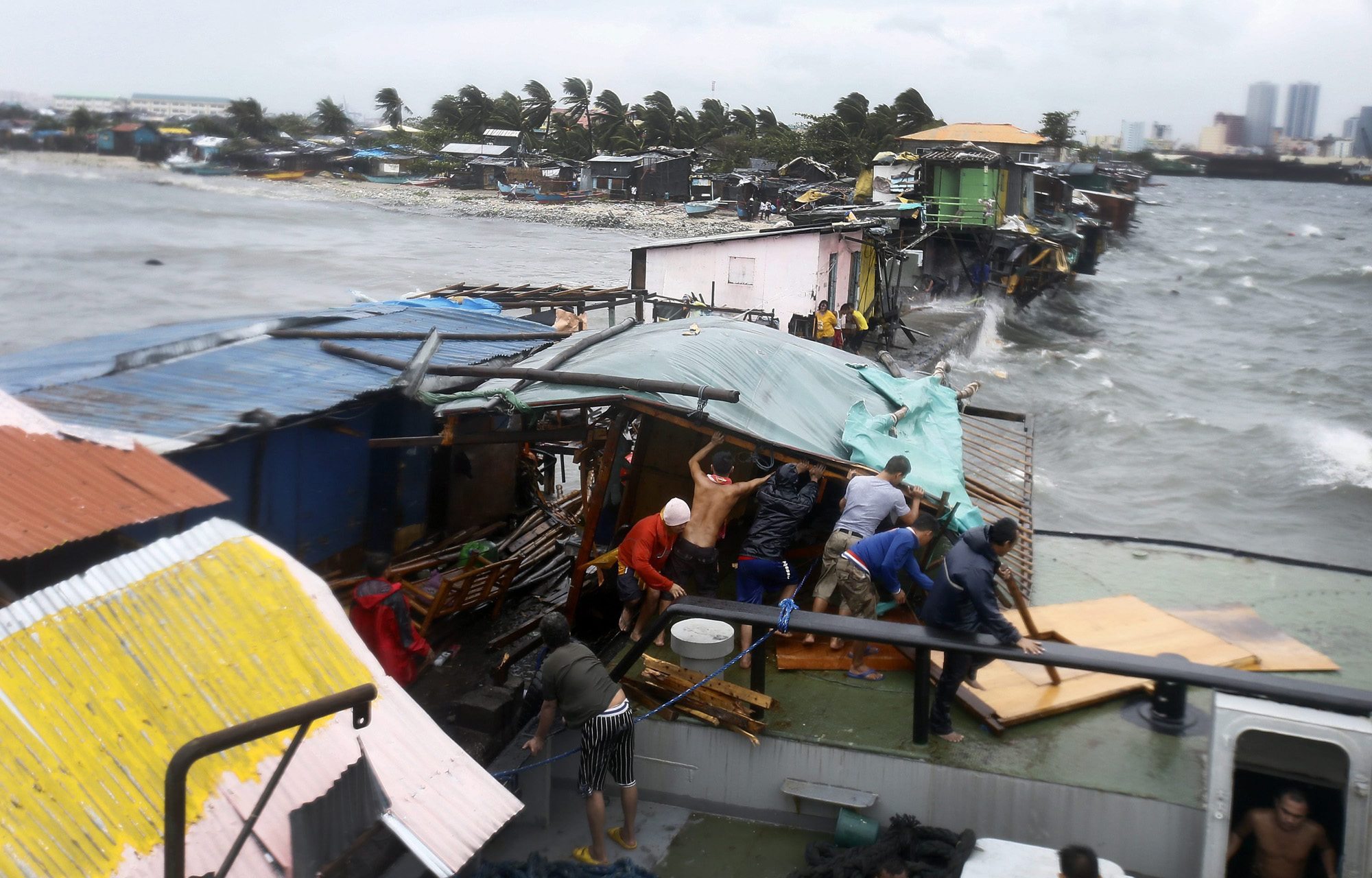 Filipino residents dismantle a shanty after it was damaged by a barged caused by strong winds and rain brought by typhoon Rammasun along the coastline of the Tondo slum area, in Manila, July 16, 2014.