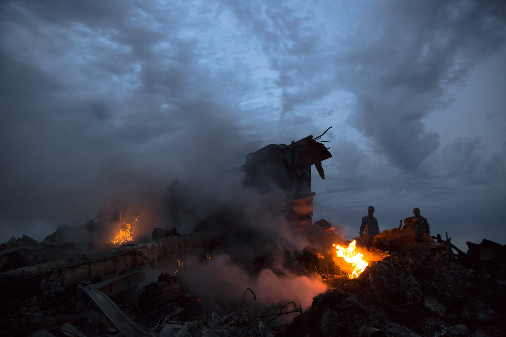 People walk amongst the debris at the crash site of a passenger plane near the village of Grabovo, Ukraine, July 17, 2014.