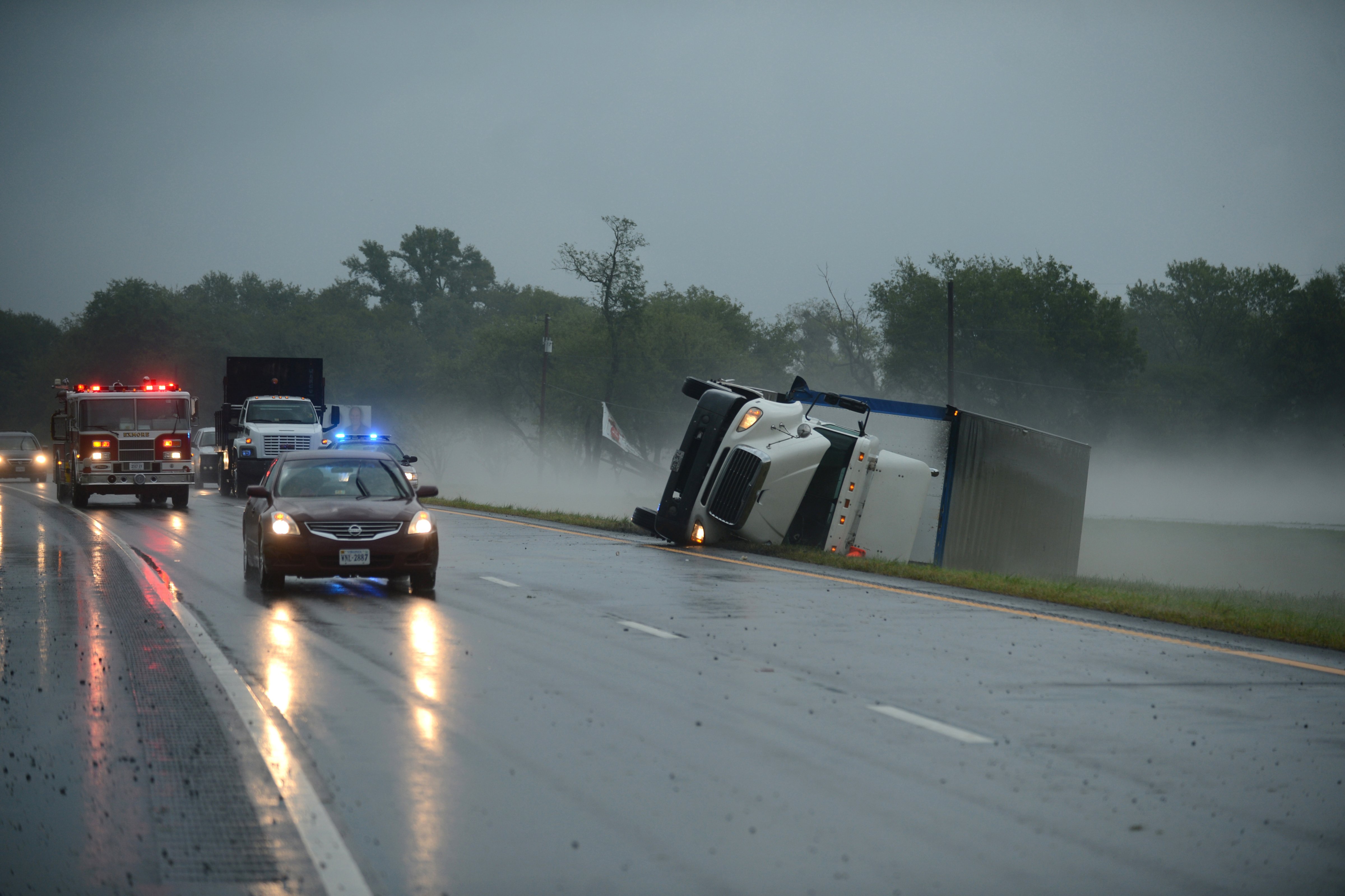 A tractor trailer truck lies on its side in the median of U.S. Route 13 while a fire engine responds to a nearby campground after a severe storm passed through the area, Cheriton, Va, July 24, 2014. (Jay Diem—Eastern Shore News/AP)