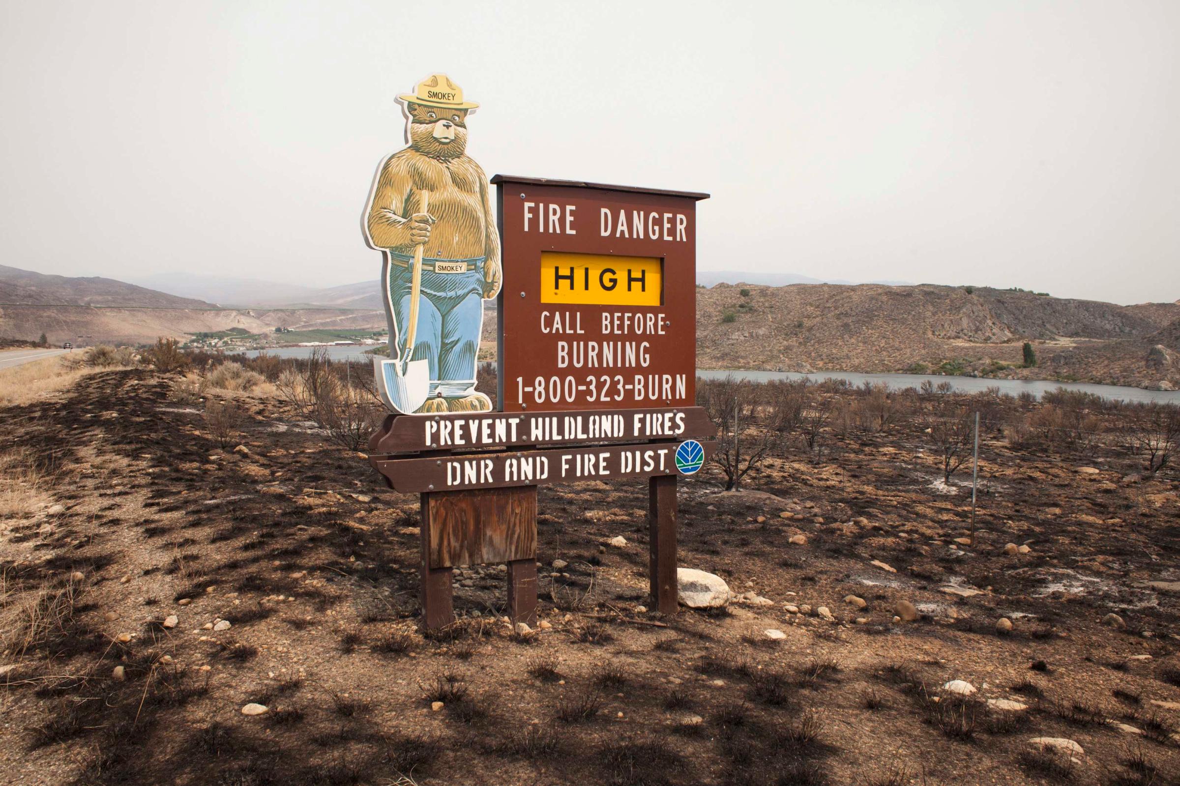 A sign surrounded by scorched earth warns drivers of the high fire danger along US State Route 97 after it was hit by the Carlton Complex fire near Pateros