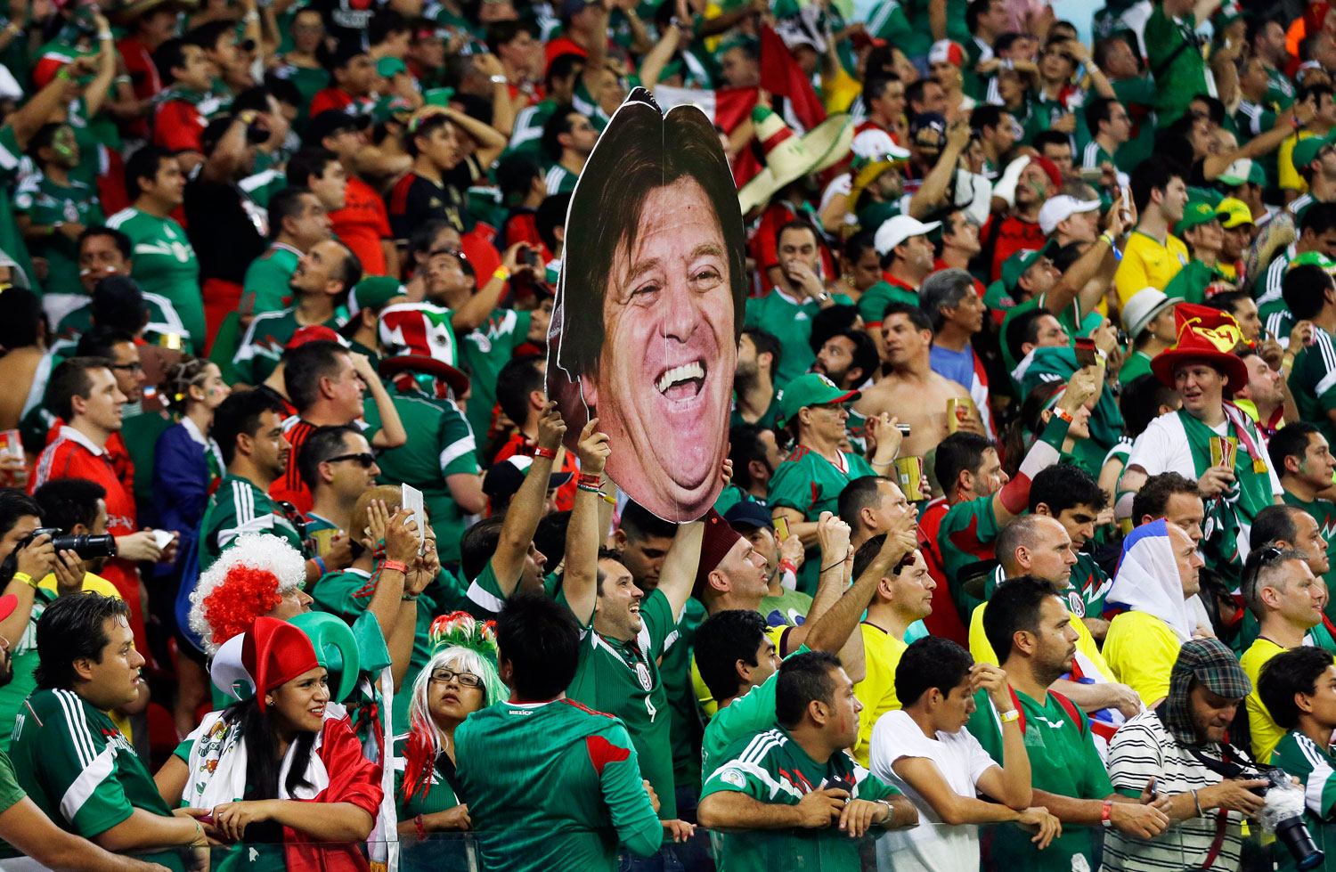 Mexico's fans celebrate holding a mask of Mexico's head coach Miguel Herrera after the match between Croatia and Mexico at the Arena Pernambuco in Recife, Brazil on June 23, 2014.