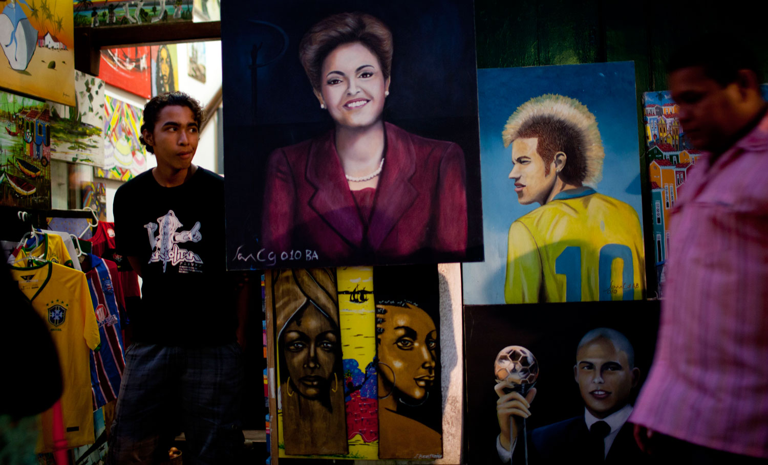 A man stands outside a shop selling paintings of Brazil's President Dilma Rousseff and Brazil's soccer player Neymar along a street decorated for the World Cup in the Pelourinho neighborhood of Salvador, Brazil on June 15, 2014.
