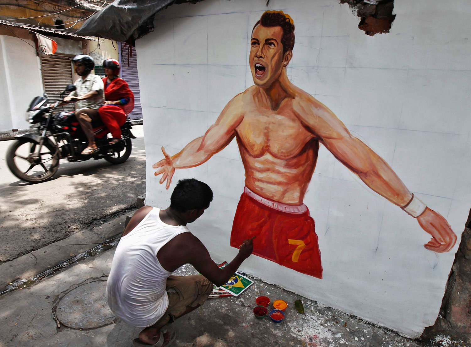 An artisan paints the wall of a house with a picture of Portugal's national soccer player Cristiano Ronaldo, in Kolkata on June 12, 2014.