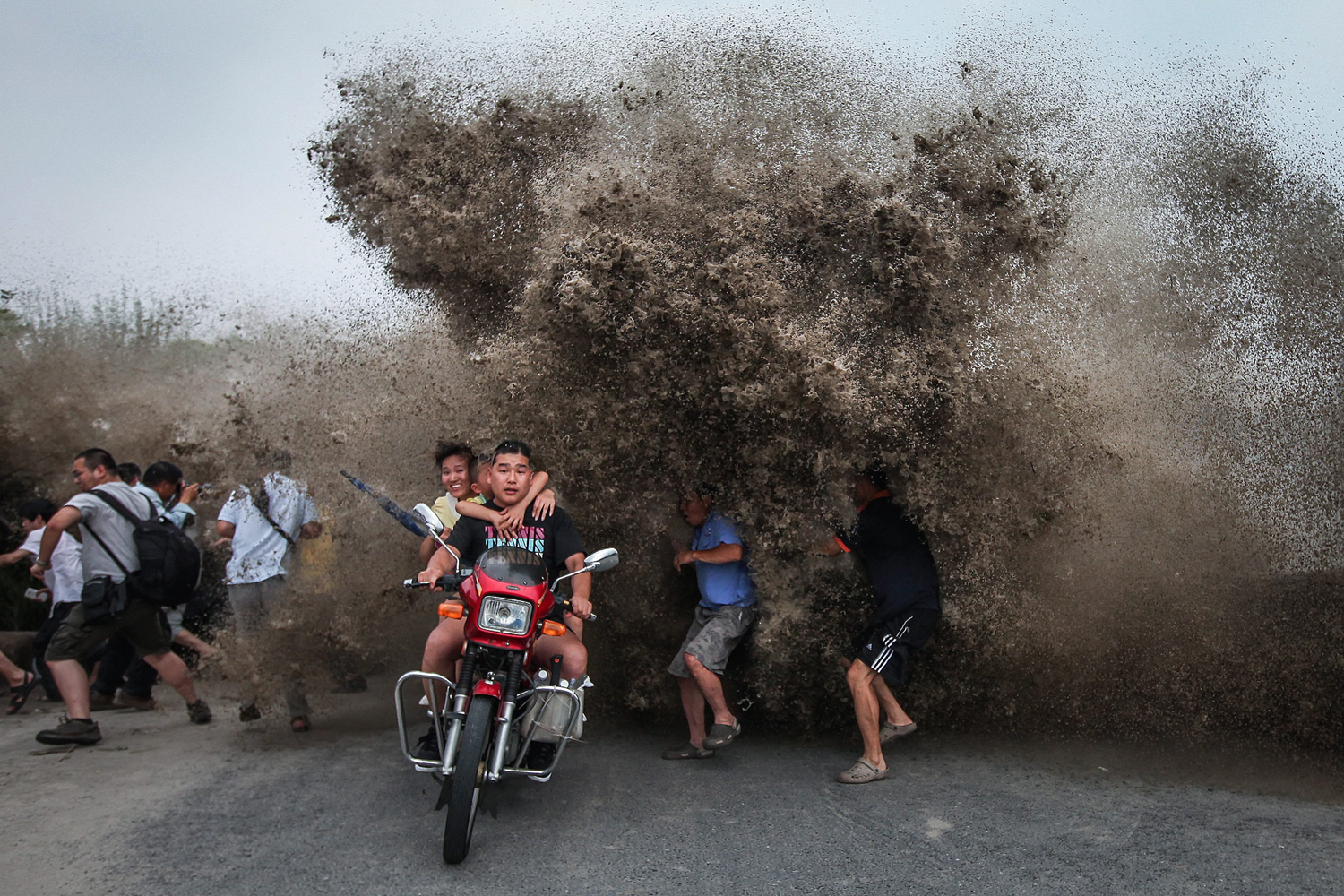 Aug. 13, 2014.  Tide spectators react to a high wave hitting the bank of Qiantang River in Hangzhou, Zhejiang province, China.