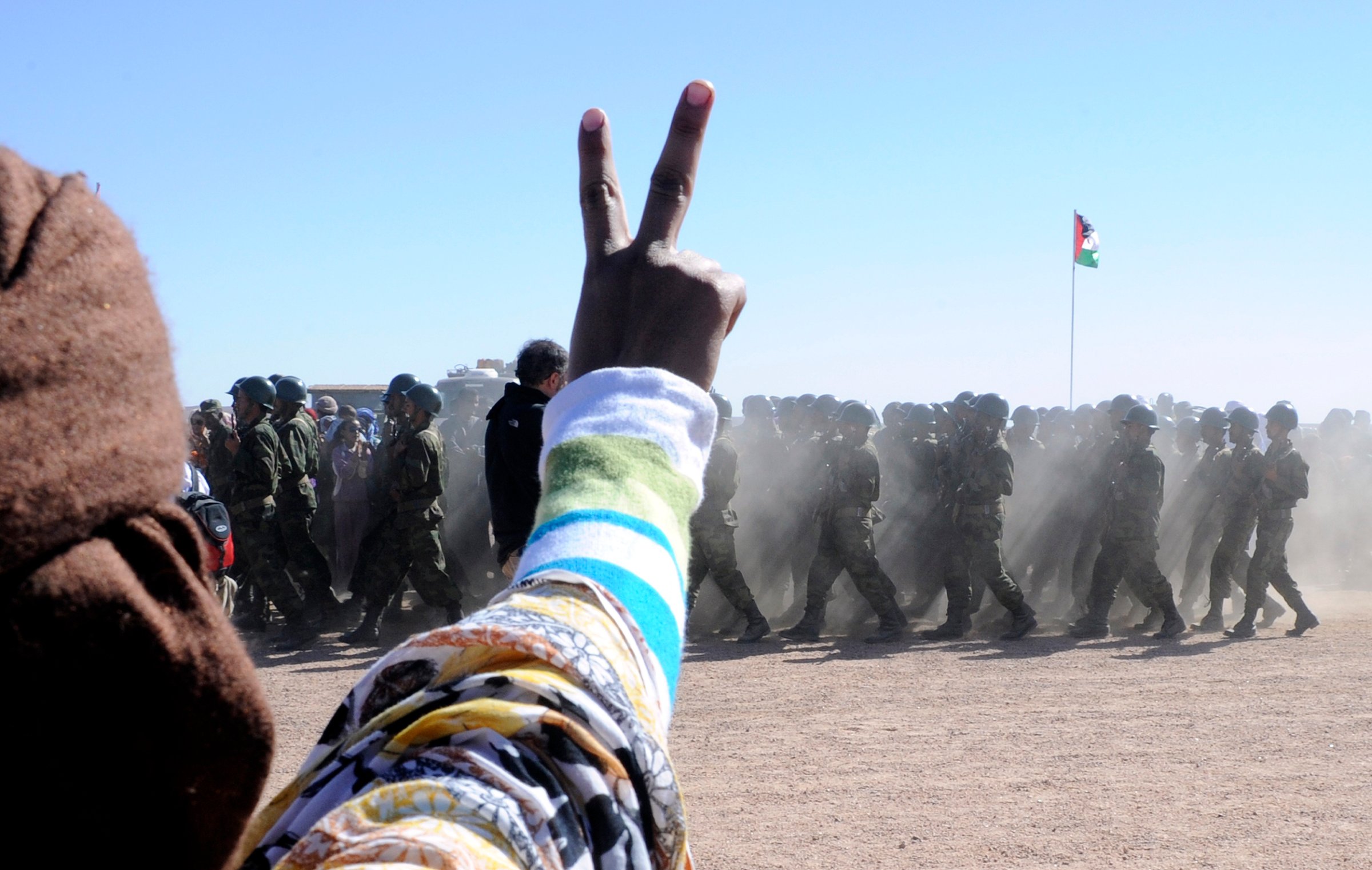 A man flashes a v-sign as soldiers from
