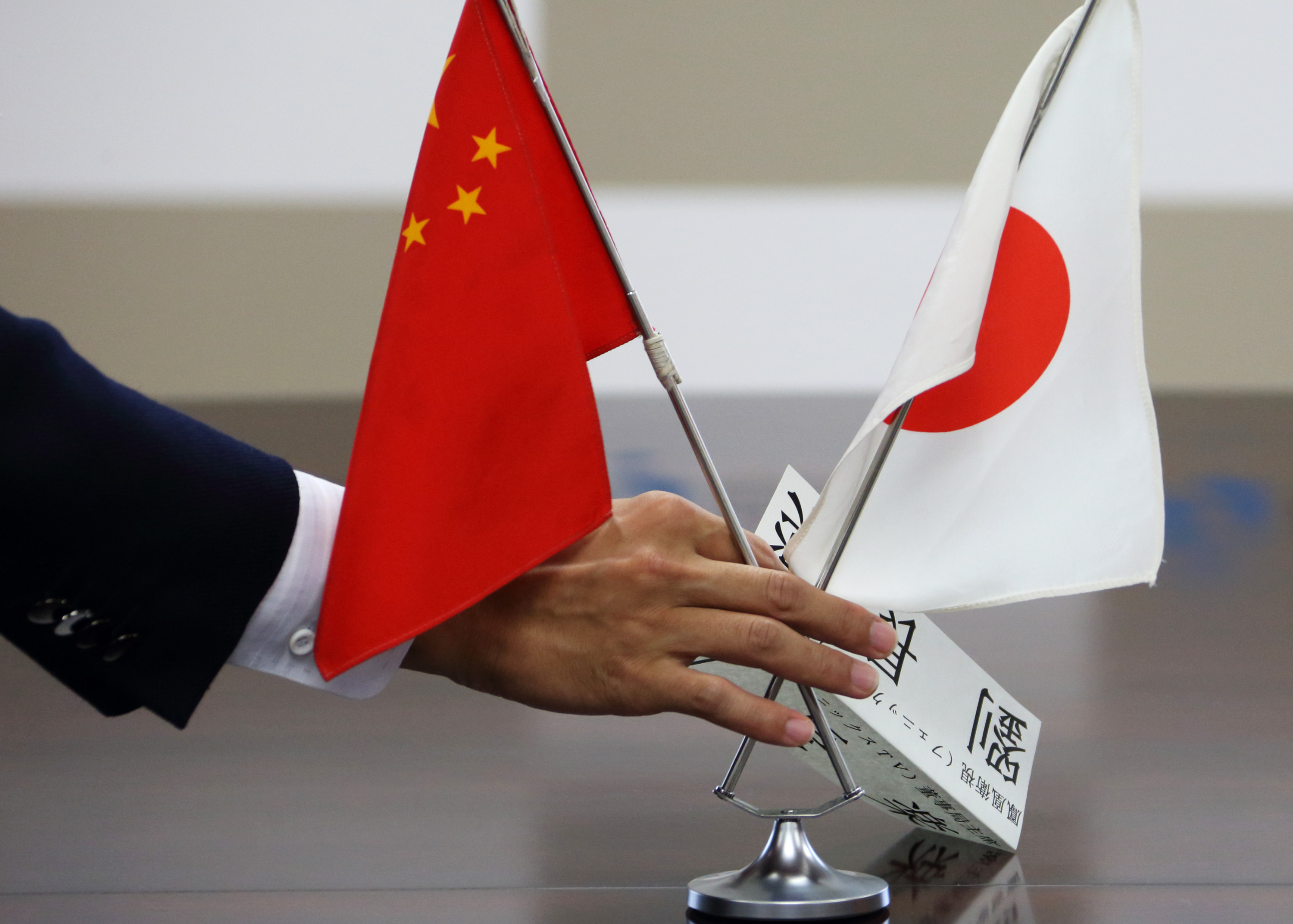 A staff member of Japan's Ministry of Economy, Trade and Industry arranges Chinese and Japanese flags before a meeting with a group of Chinese business leaders in Tokyo on Sept. 26, 2013 (Bloomberg/Getty Images)