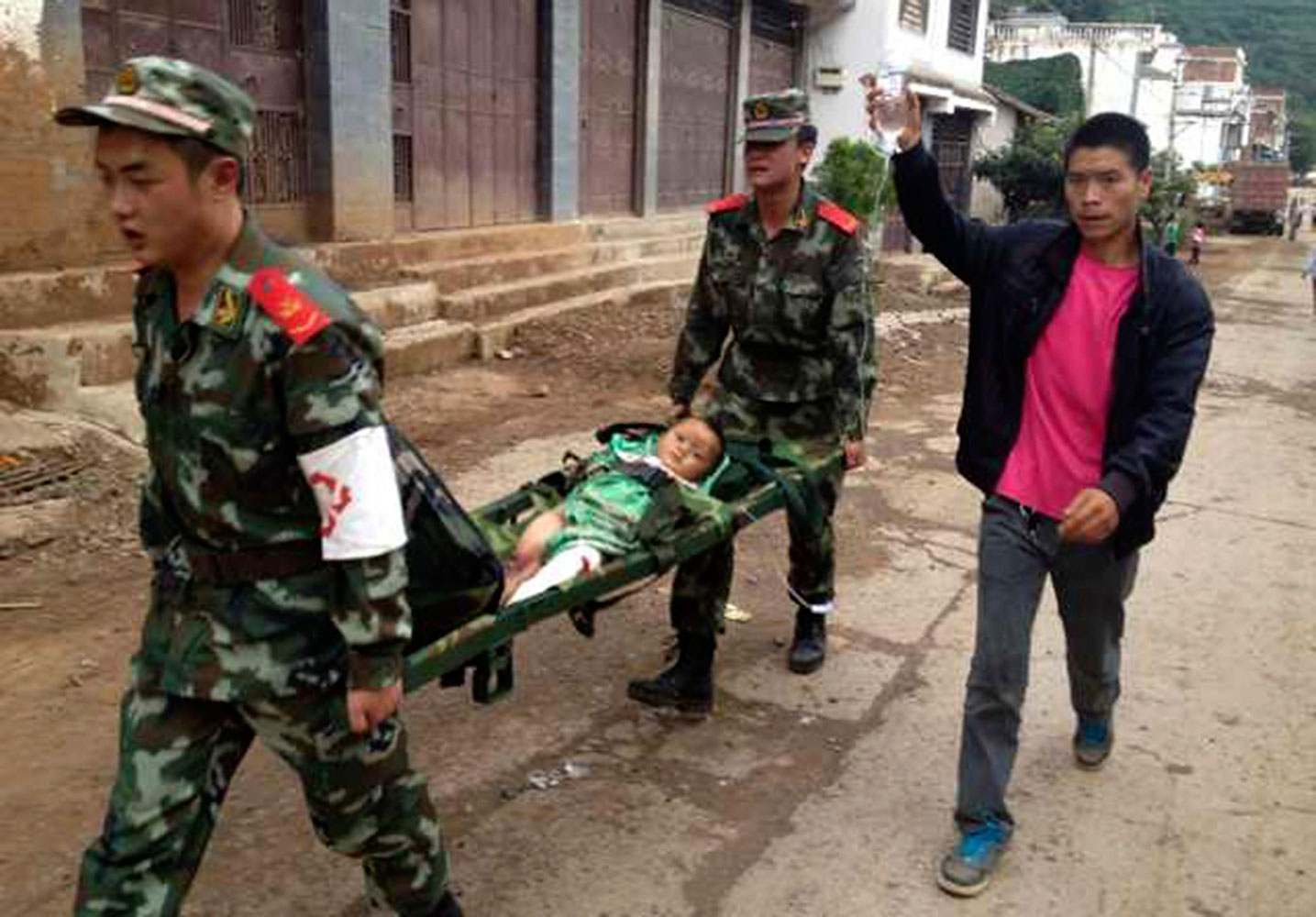 Paramilitary policemen carry an injured child on a stretcher after an earthquake hit Longtoushan township of Ludian county