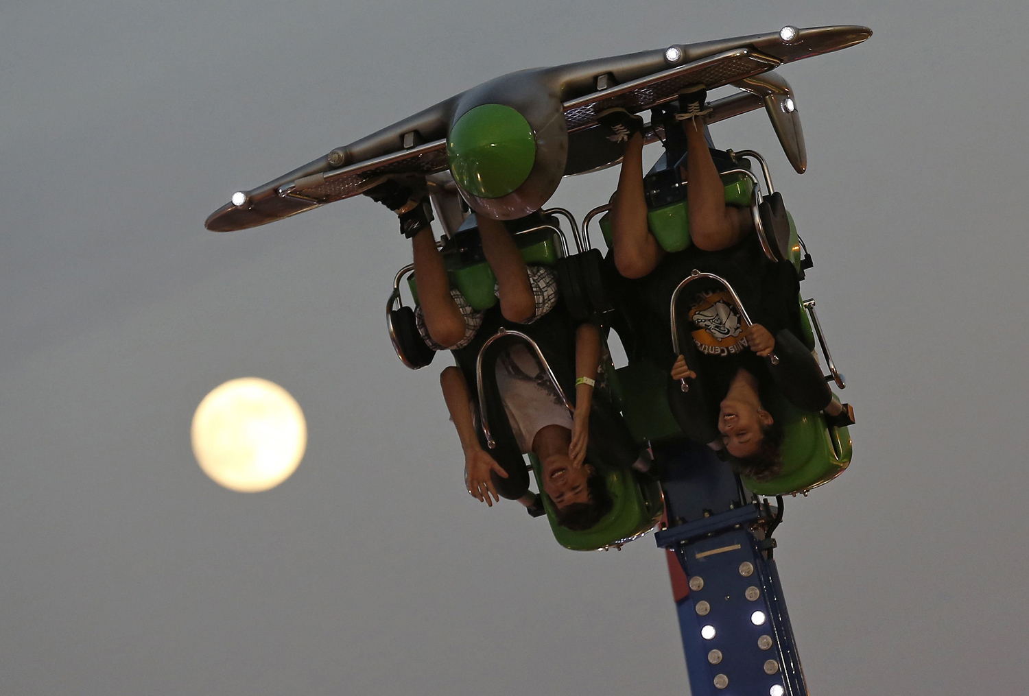 Aug. 9, 2014. The moon is seen in the background as people ride upside down at the Wisconsin State Fair in West Allis, Wisconsin.