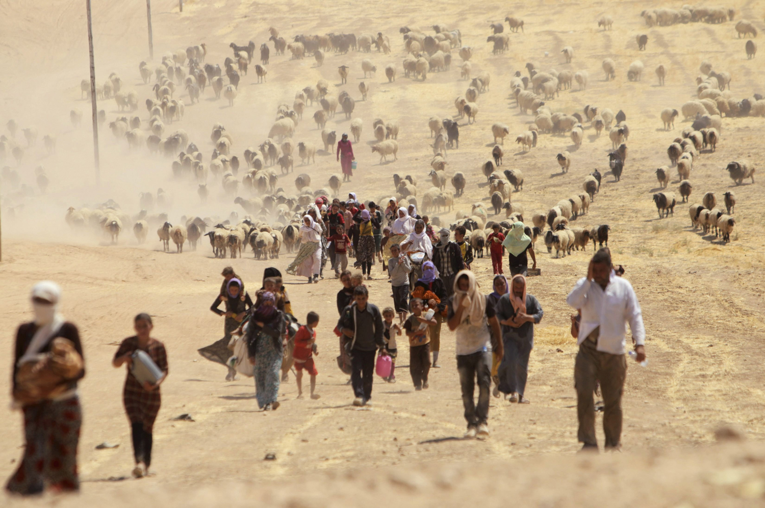 Aug. 10, 2014. Displaced people from the minority Yezidi sect, fleeing violence from forces loyal to the Islamic State in Sinjar town, walk towards the Syrian border, on the outskirts of Sinjar mountain, near the Syrian border town of Elierbeh of Al-Hasakah Governorate.