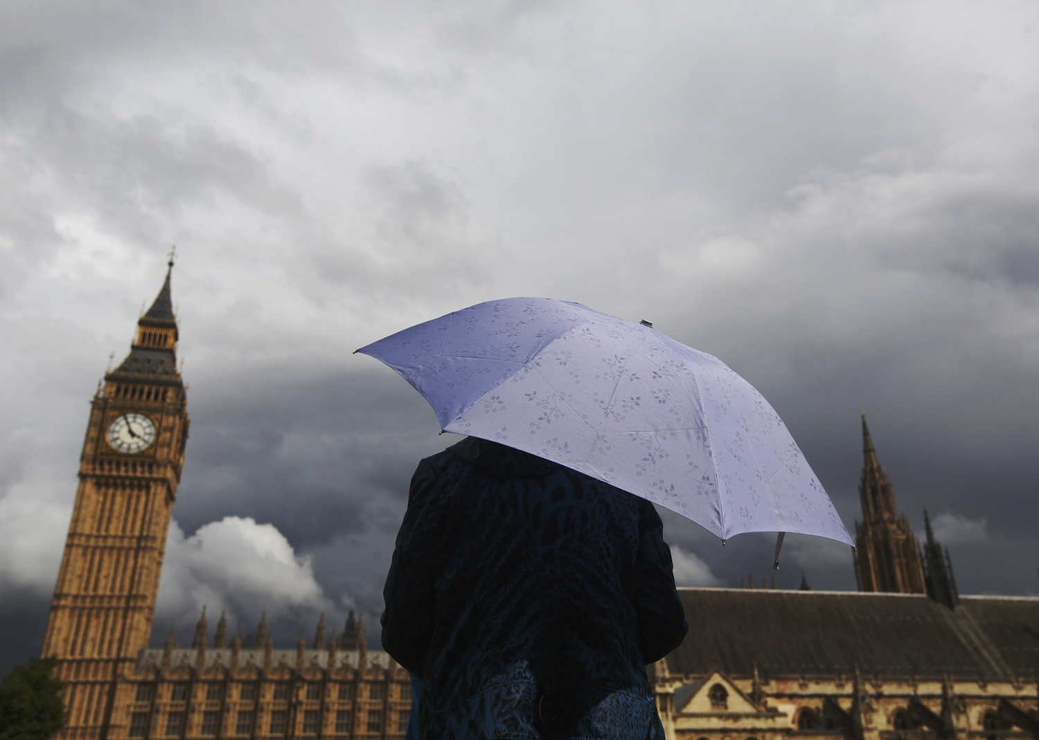 Aug. 11, 2014. A woman looks towards dark clouds over the Houses of Parliament in central London.
