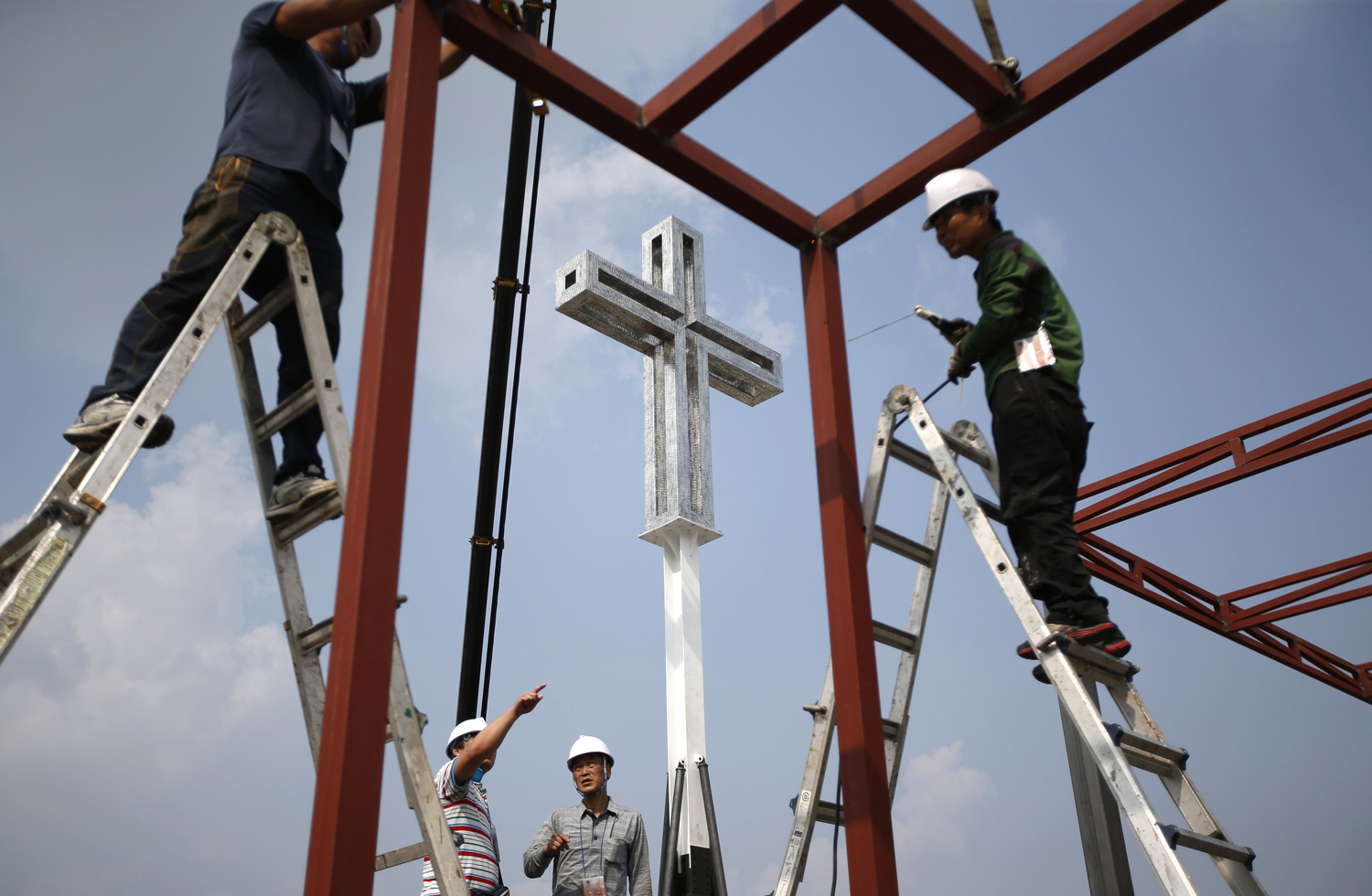 Aug. 12, 2014. A giant cross is seen as labourers work to assemble a stage in front of Gwanghwamun, main gate of the royal Gyeongbok Palace, ahead of Pope Francis' visit in central Seoul.